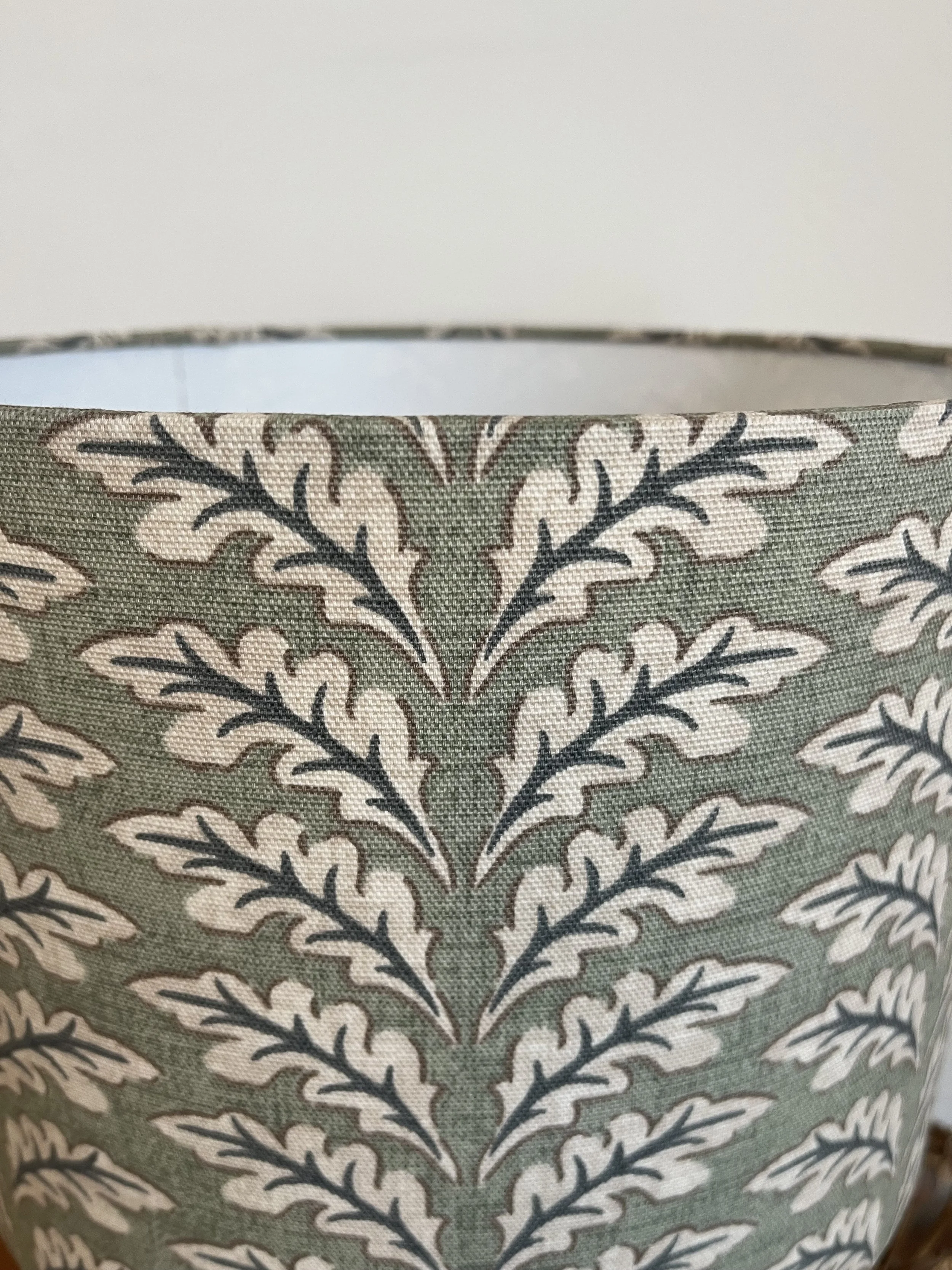 Close up of leaves, cream and grey on sage green fabric.