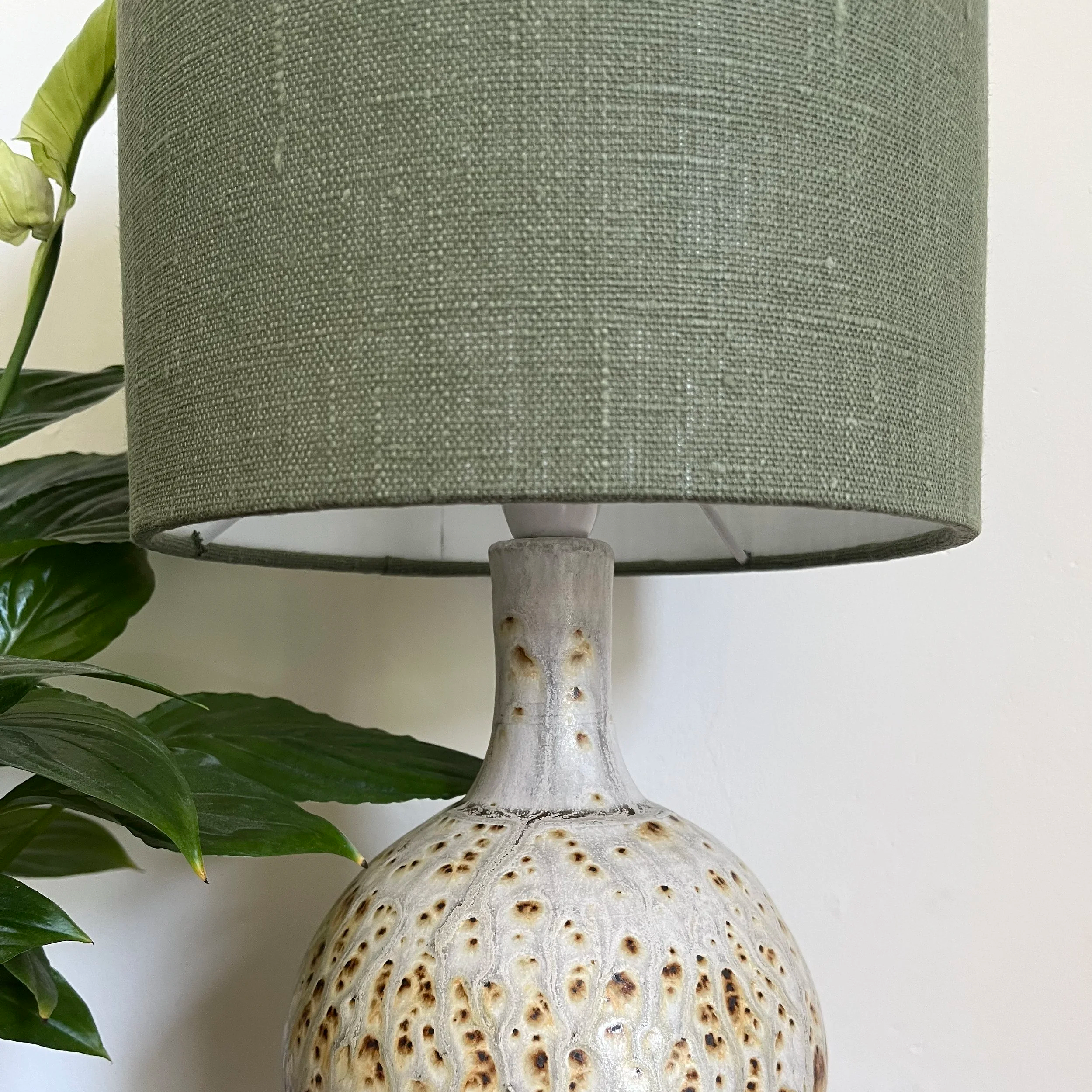 Close up of the texture of the dusky, dark green linen of the lamp shade.