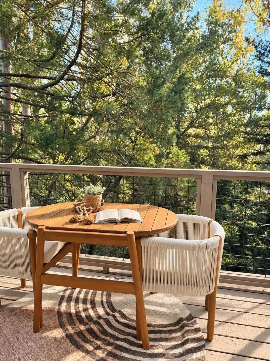 Outdoor patio home staging in Bellevue, WA, featuring a natural wood dining table, modern woven chairs, and a peaceful tree-lined deck by White Harmony Design & Staging.