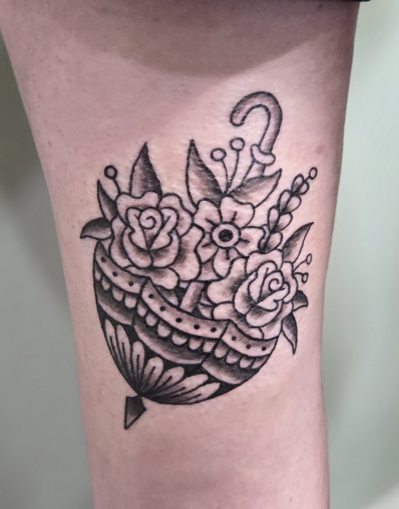Black and gray tattoo of a fish with flowers and leaves.