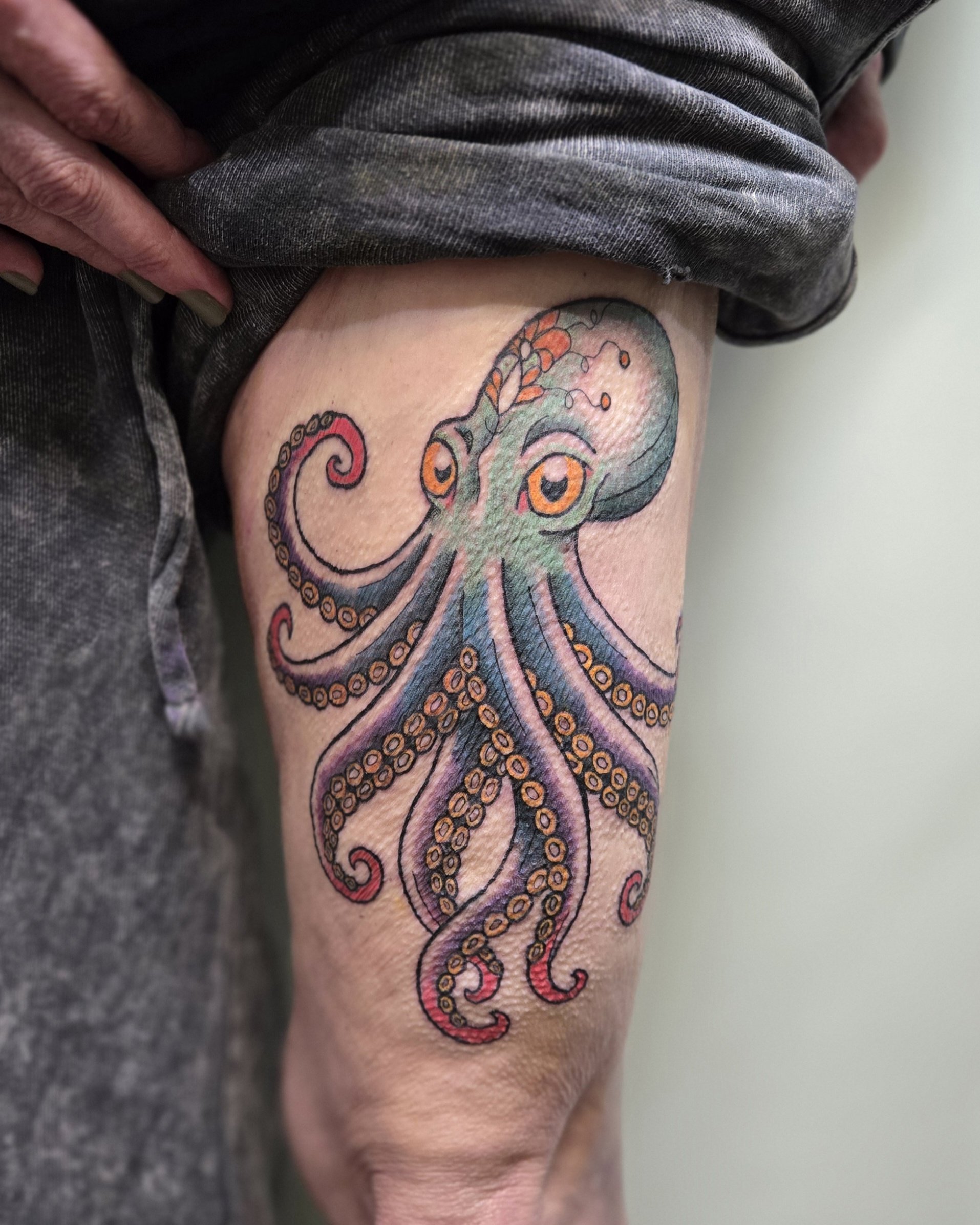 Colorful tattoo of an octopus on a person’s thigh.
