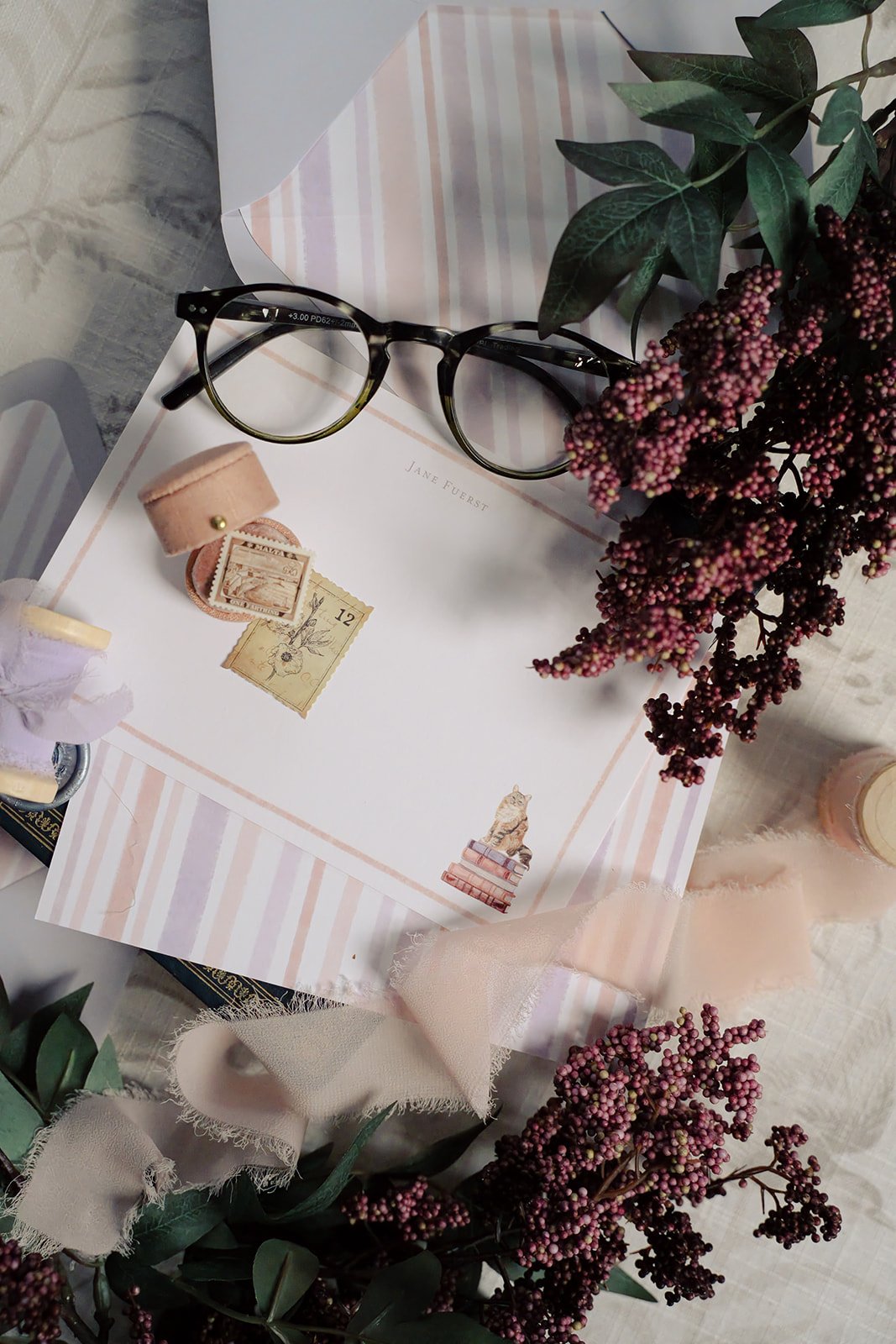 Cat stationery with a cat sitting on a stack of pink and purple books