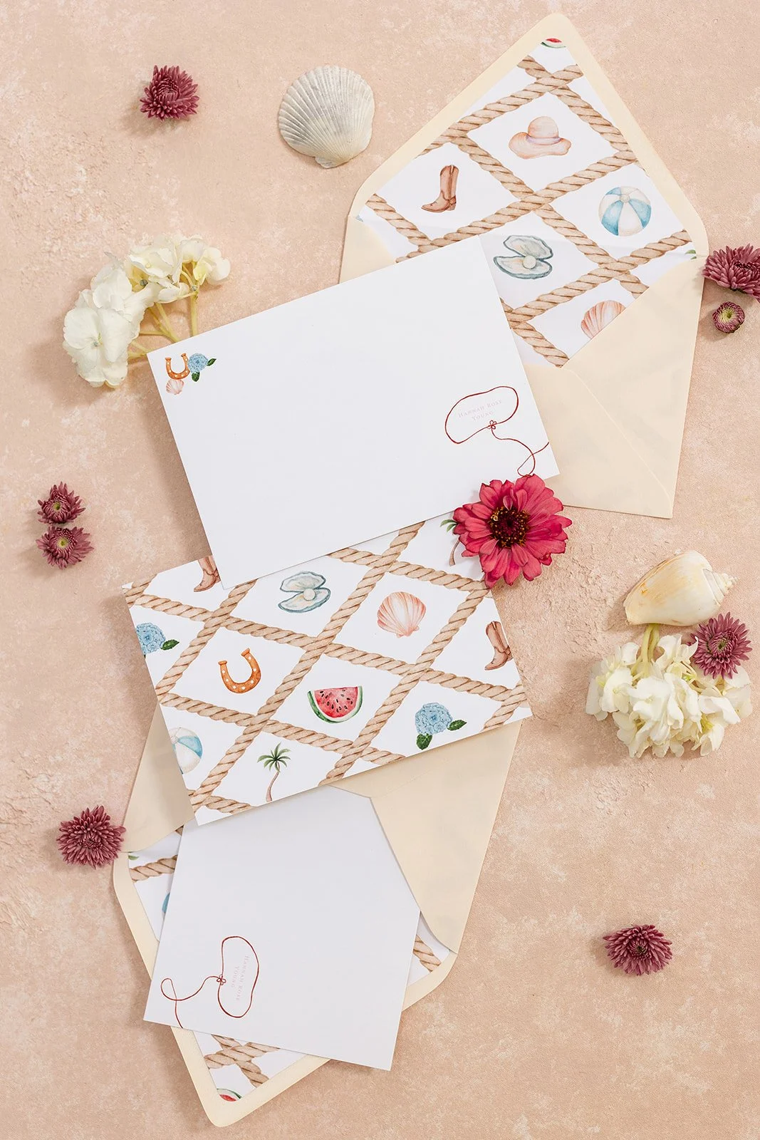 Set of envelopes and cards with a beach-themed design, surrounded by flowers and seashells.