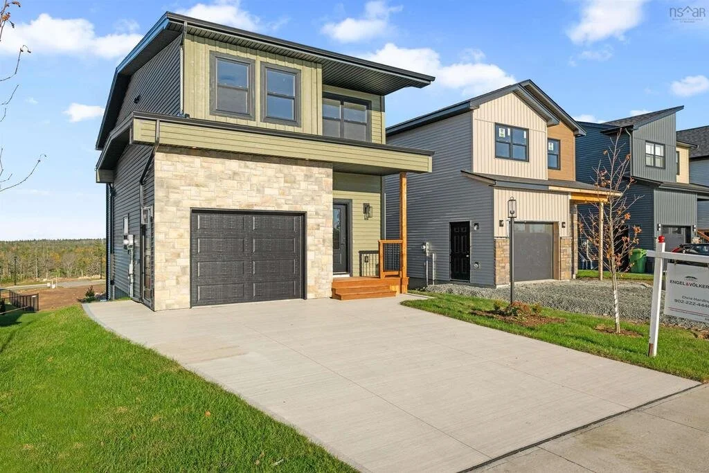 A modern two-story house with a stone garage and a small front porch, located in a suburban neighborhood with similar houses nearby.