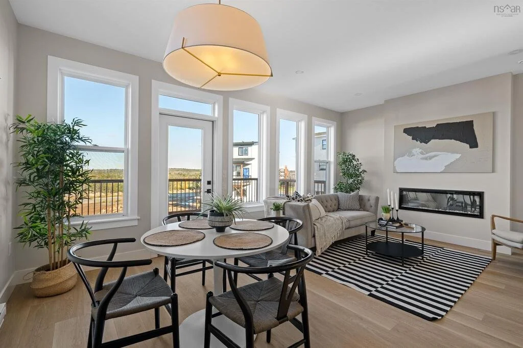 Bright living room with large windows, a beige sofa, a black and white striped rug, and modern decor on walls and tables.