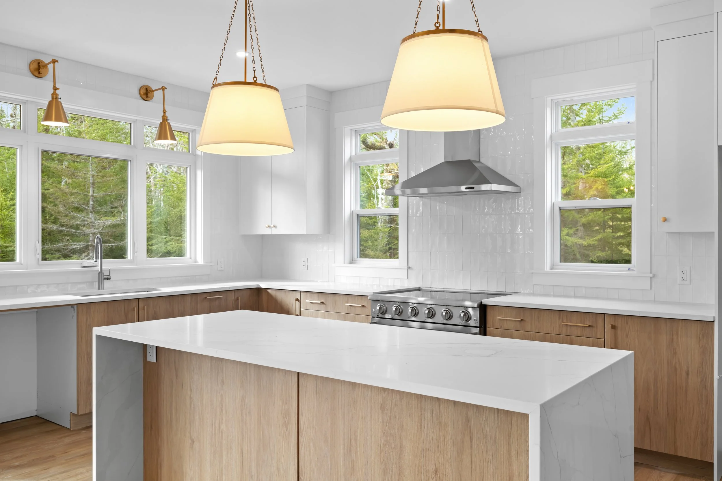 Modern kitchen design with waterfall countertops, custom backsplash, and large island pendants 