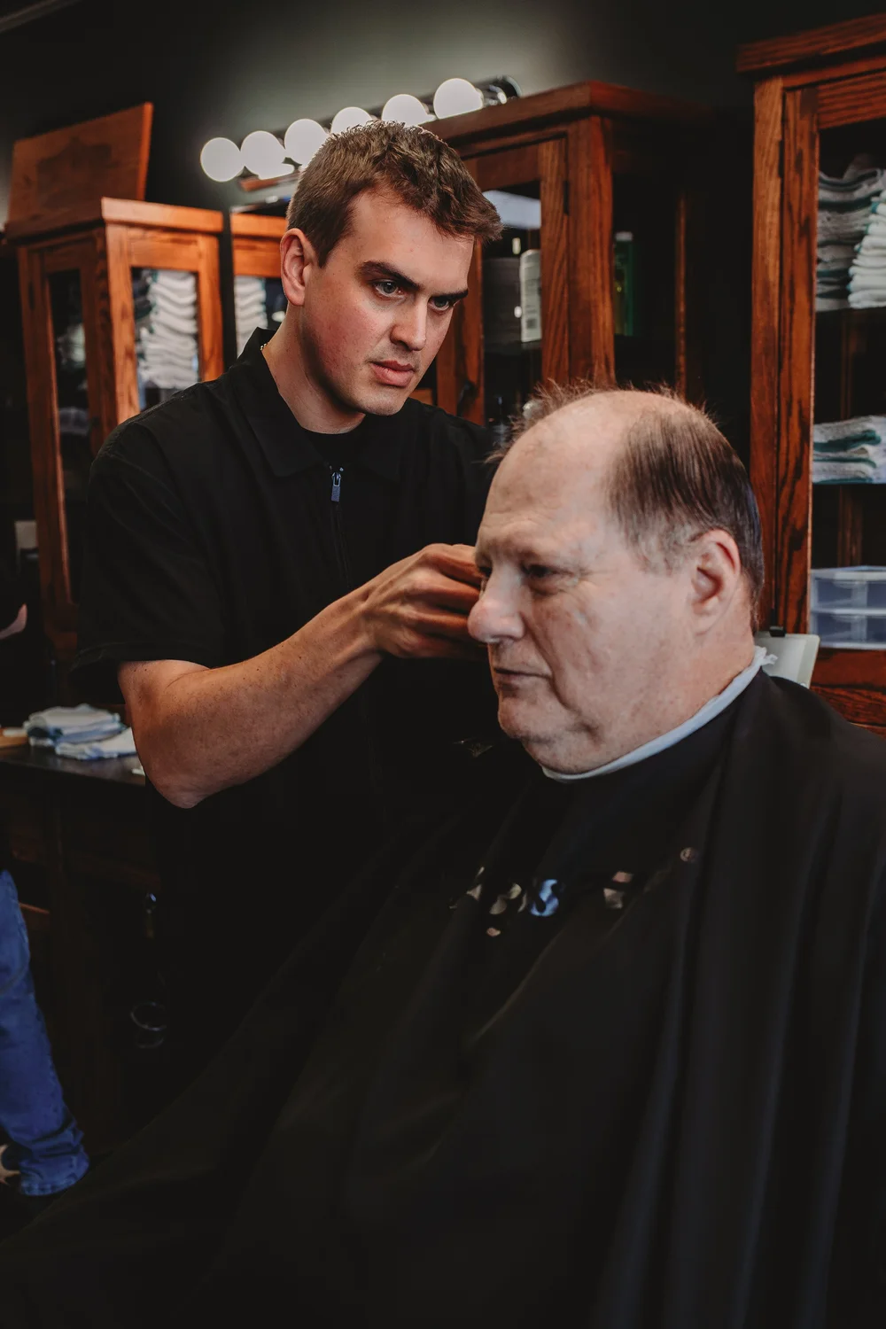 Barber finishing a cut at Three Hounds Barbershop