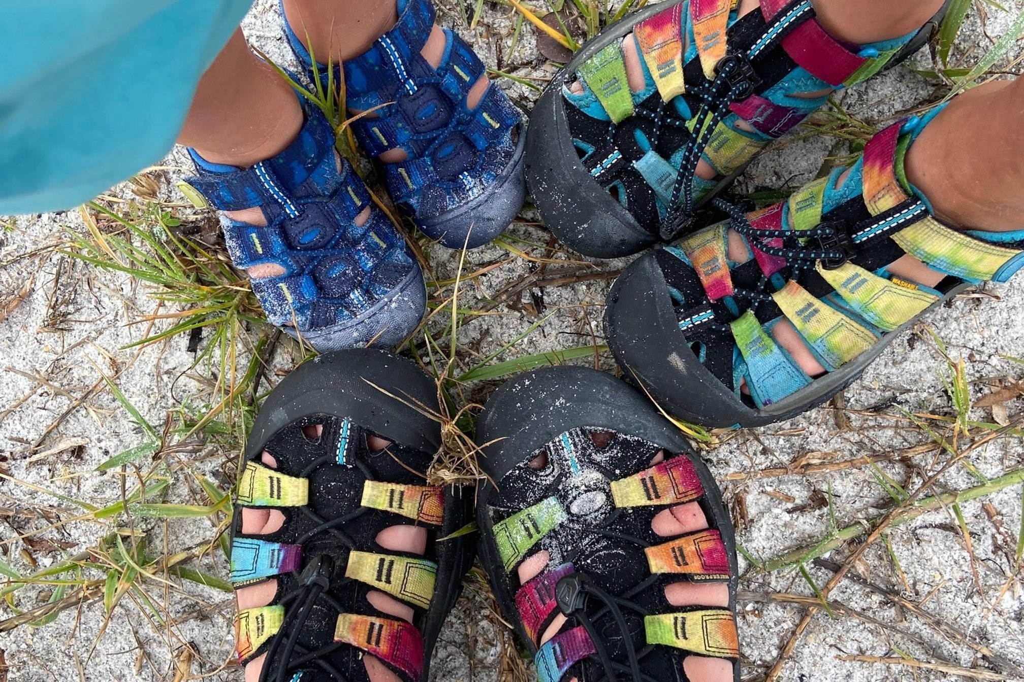2 pairs of Keen hiking sandals in a circle with sand on them