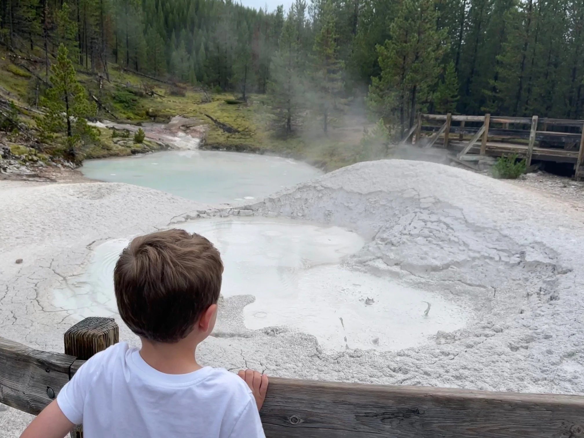 The author's son looks at the bubbling mud pots on a trail in Yellowstone National Park