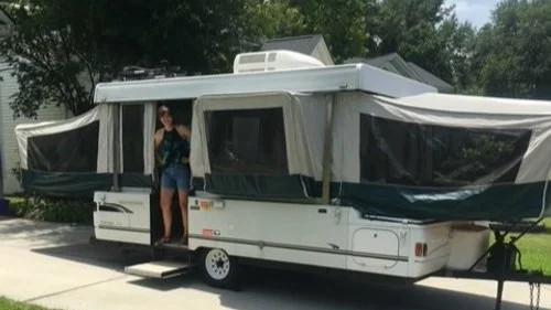 Crater Lake inside Crater Lake National Park surrounded by green pine trees and mountainous cliffs with a small island in the middle.