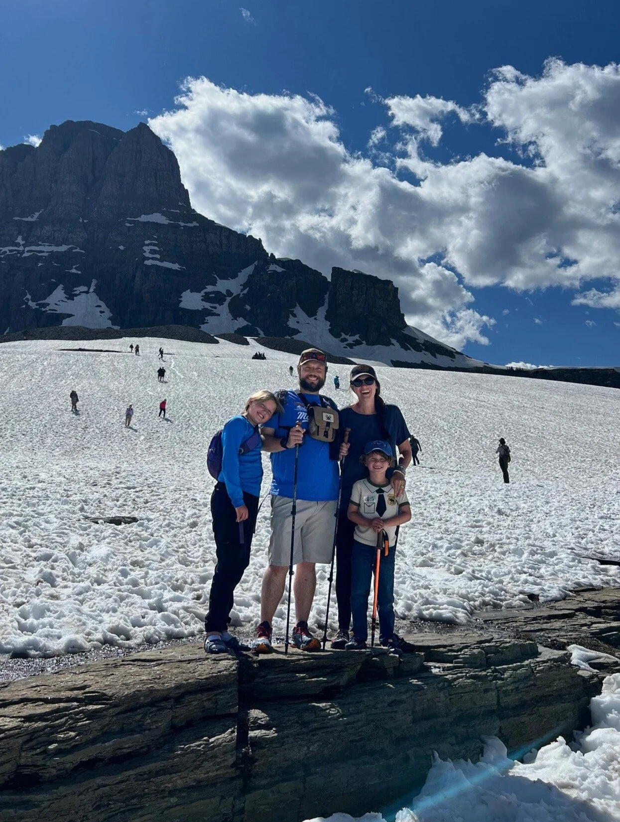 The author and her family stand on a rock amid an expanse of snow in Glacier National Park