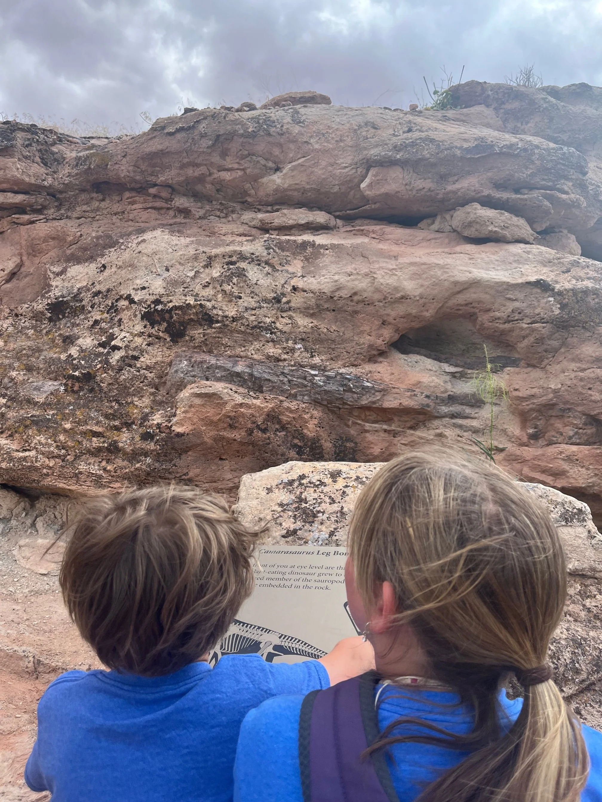 The author's children stand in front of a dinosaur leg fossil on the Mill Creek Trail in Moab