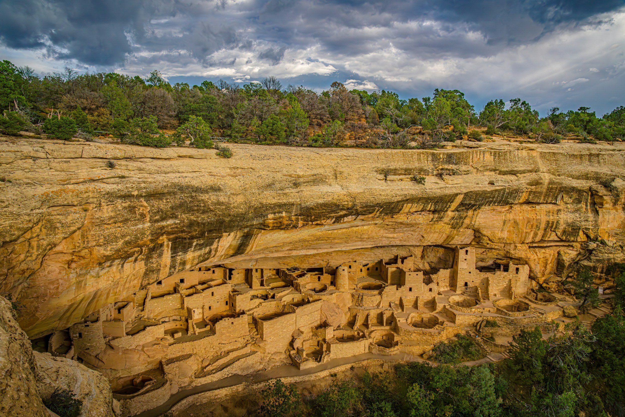 The cliff dwellings at Mesa Verde are viewed from across a canyon and from slightly above