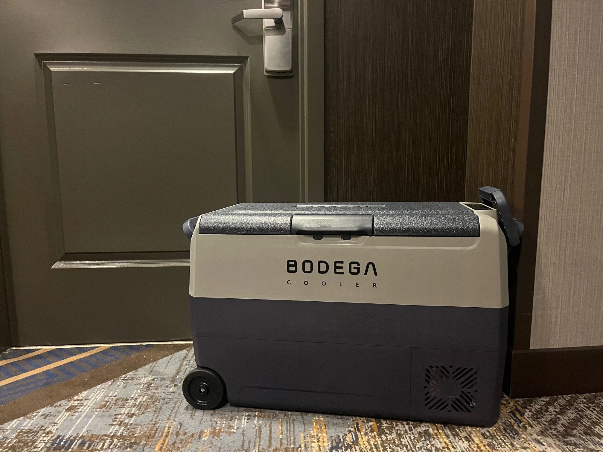 Blue and grey Bodega cooler sitting in front of a hotel room door