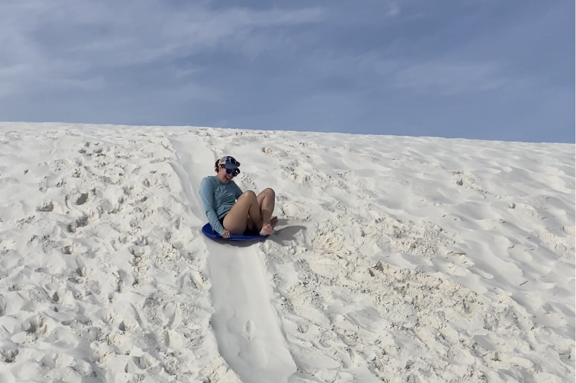 The author sleds down one of the dunes on a blue sledding saucer