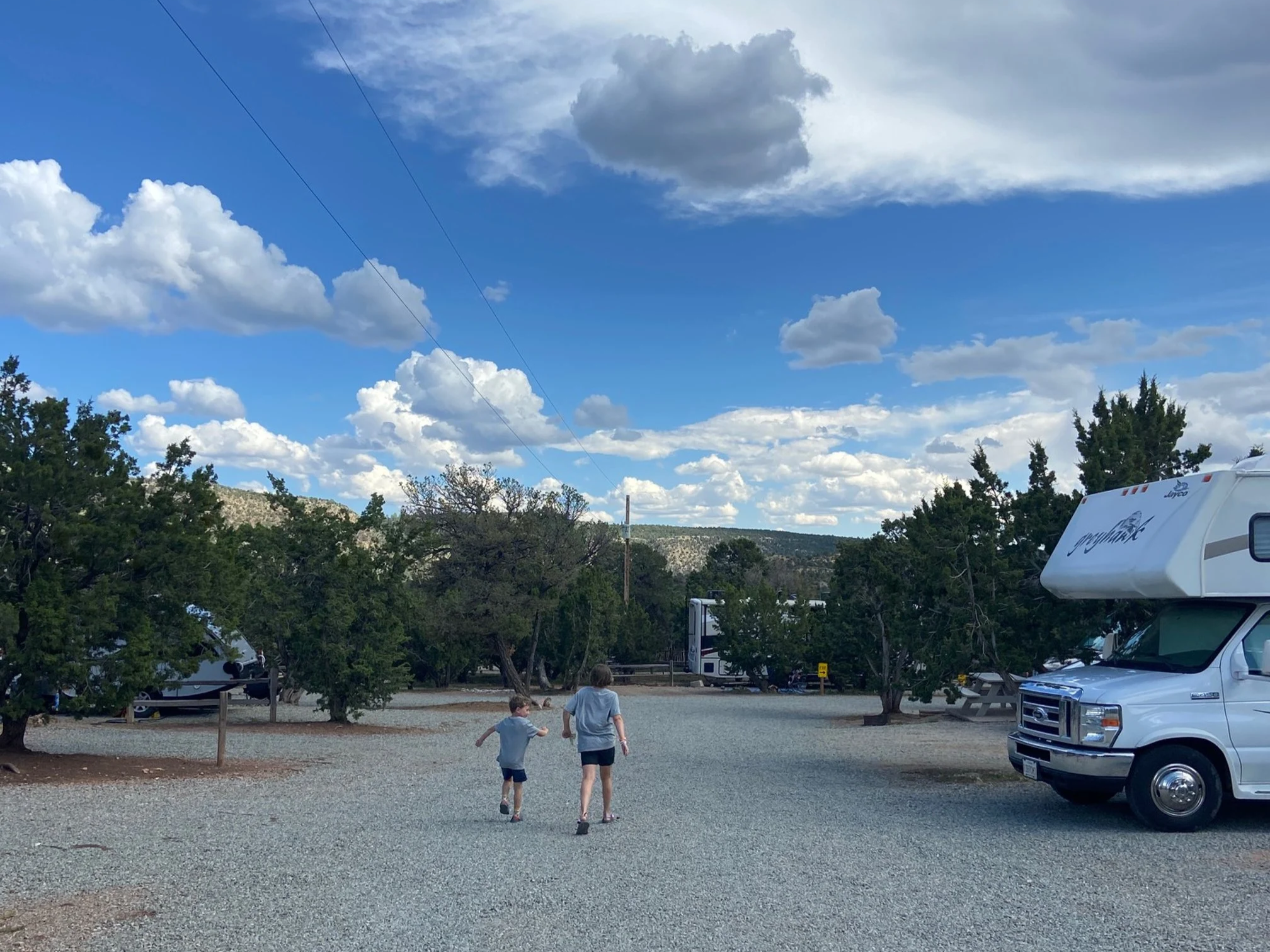 The author's children wearing grey shirts and black shorts walking on the gravel road inside Santa Fe KOA