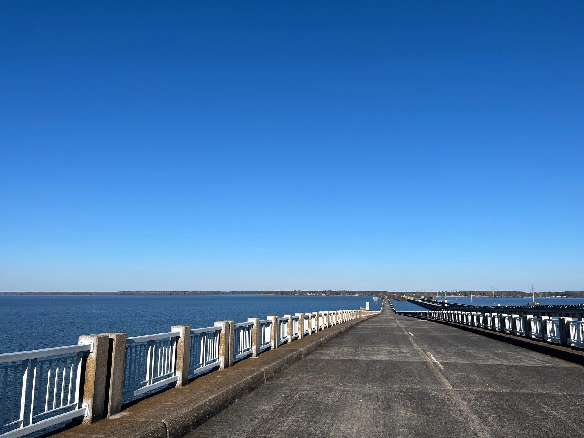 The bridge with white fencing and the blue lake on either side