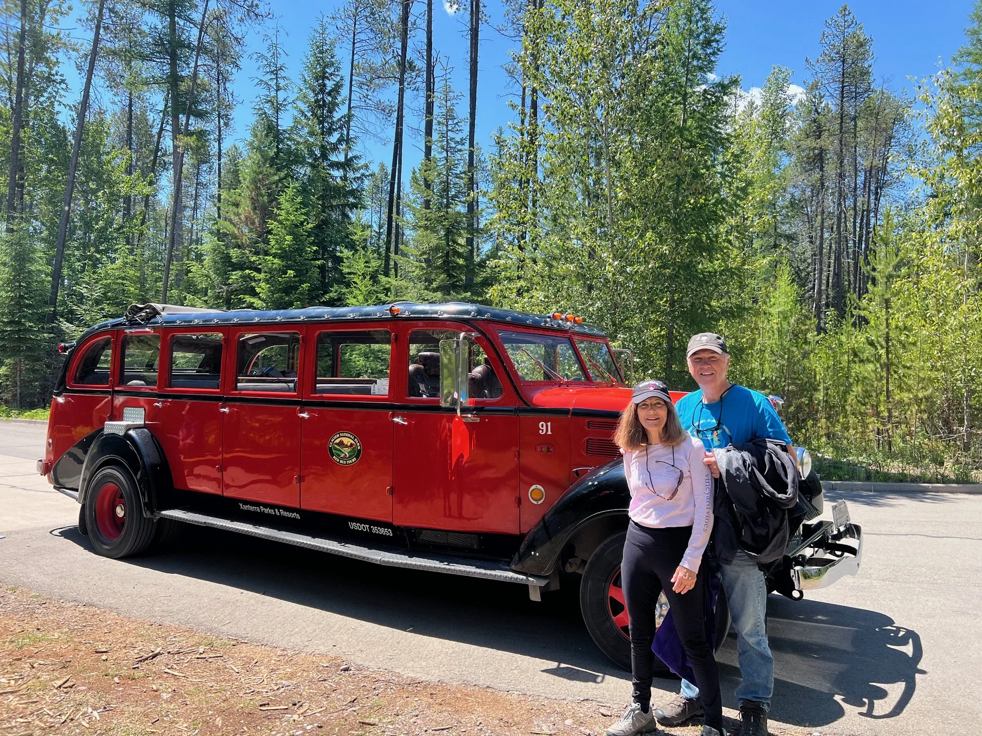 The author's parents stand in front of one of the red bus tours in Apgar Village