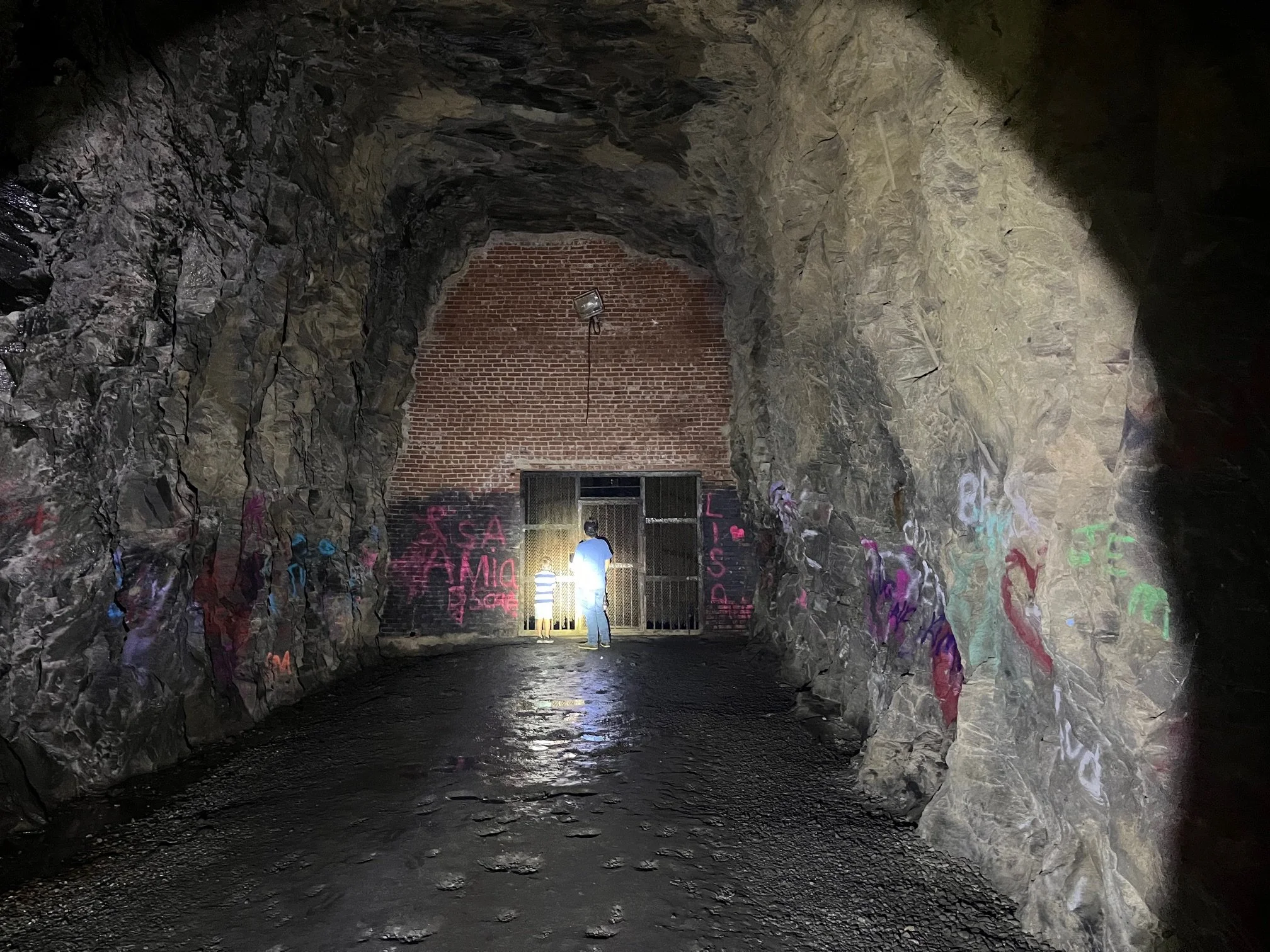 The author's son and husband stand in a beam of light inside Stumphouse Tunnel