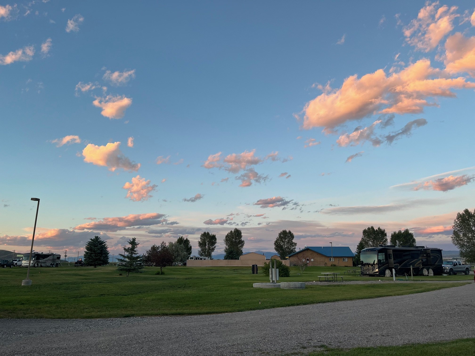 The grassy common area, visiting RV, and main office building at the Countryside RV Park in Dillon, Montana