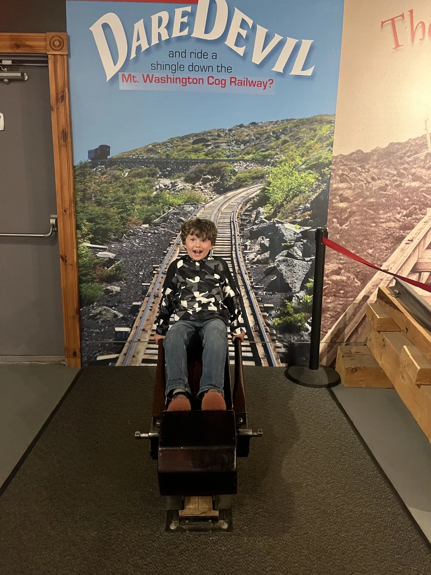 The author's son sits on a replica of the devil's shingle sleds at the museum at Mt. Washington Cog Railway
