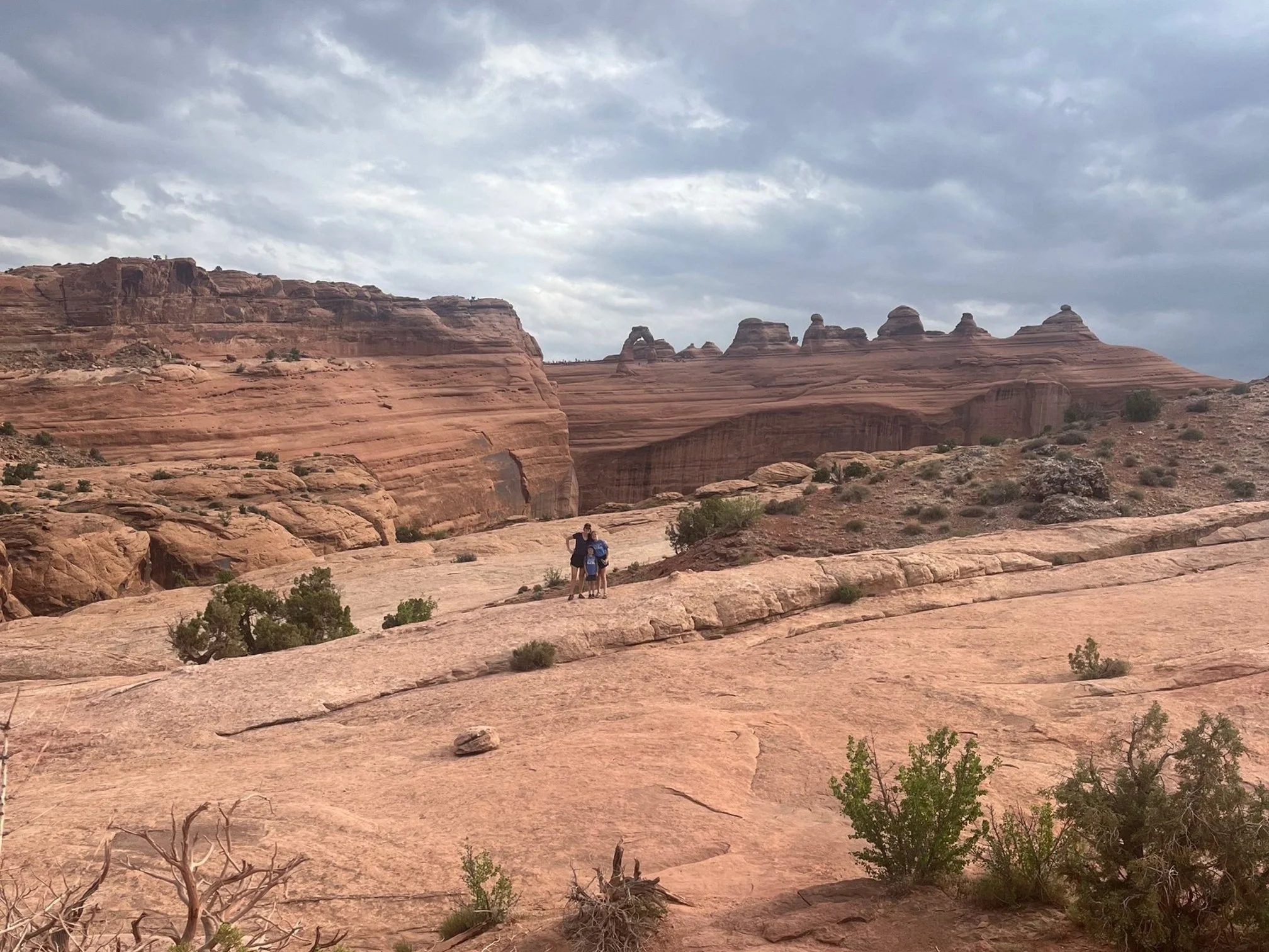 The author and her children standing in front of Delicate Arch across the canyon