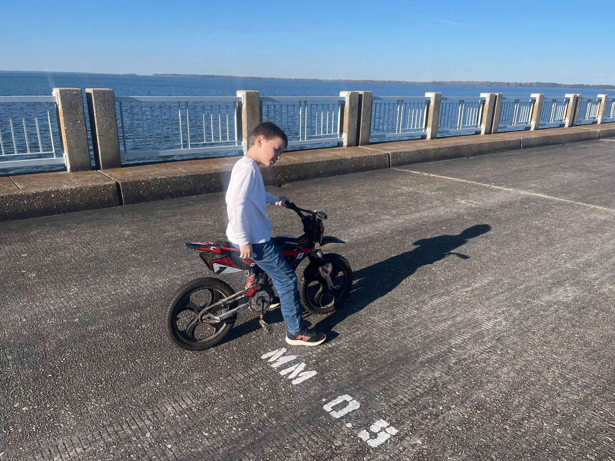 The author's son sitting on his bike next to a painted mile marker number on the bridge road bed