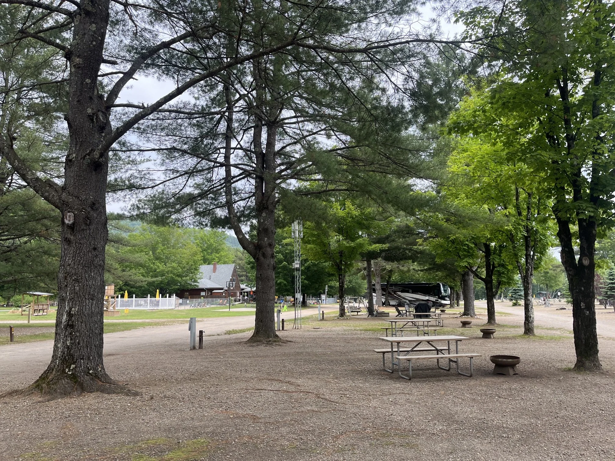 Several empty sites at the campground with the pool and the main office in the background