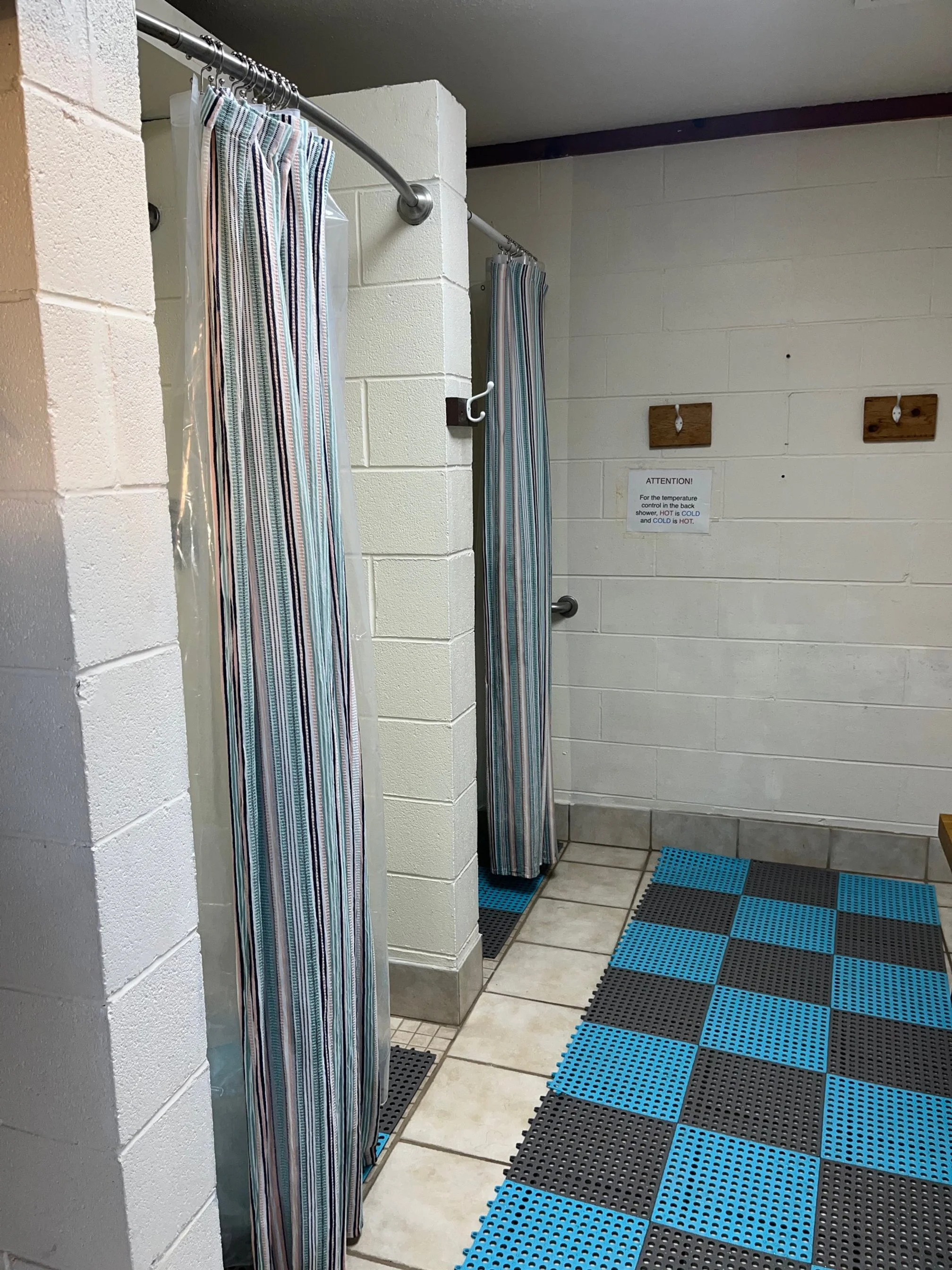 Cinderblock shower room with striped shower curtains and metal towel hooks