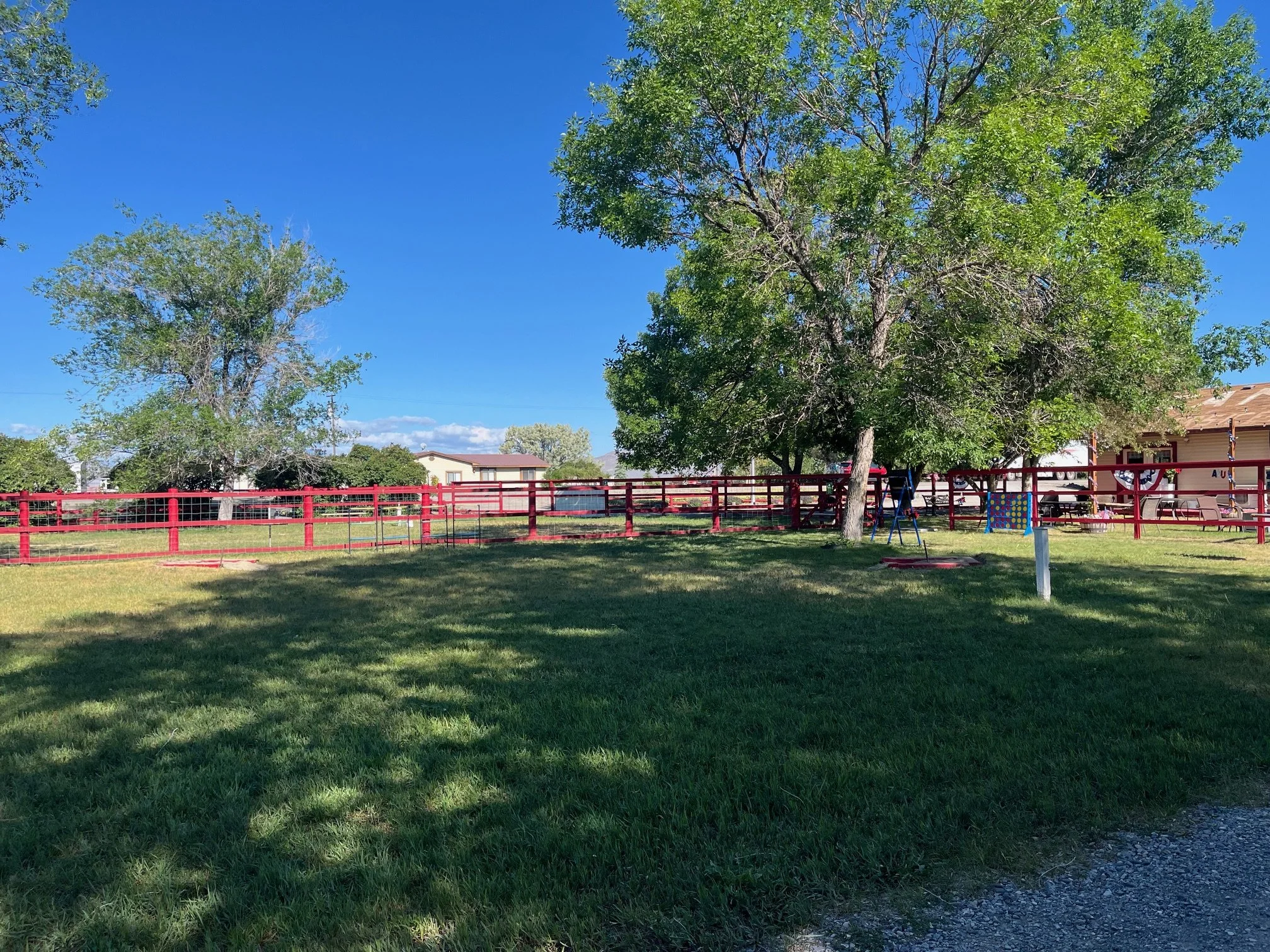 Large grassy area with red fence in the background and lawn games