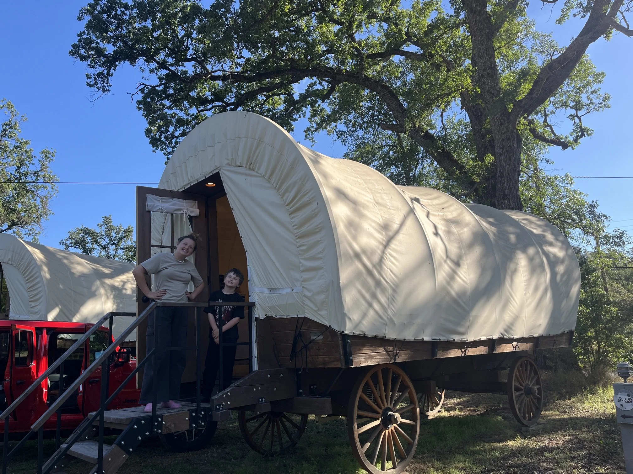 The author's children standing in the doorway of a Conestoga wagon at Yosemite Pines RV campground