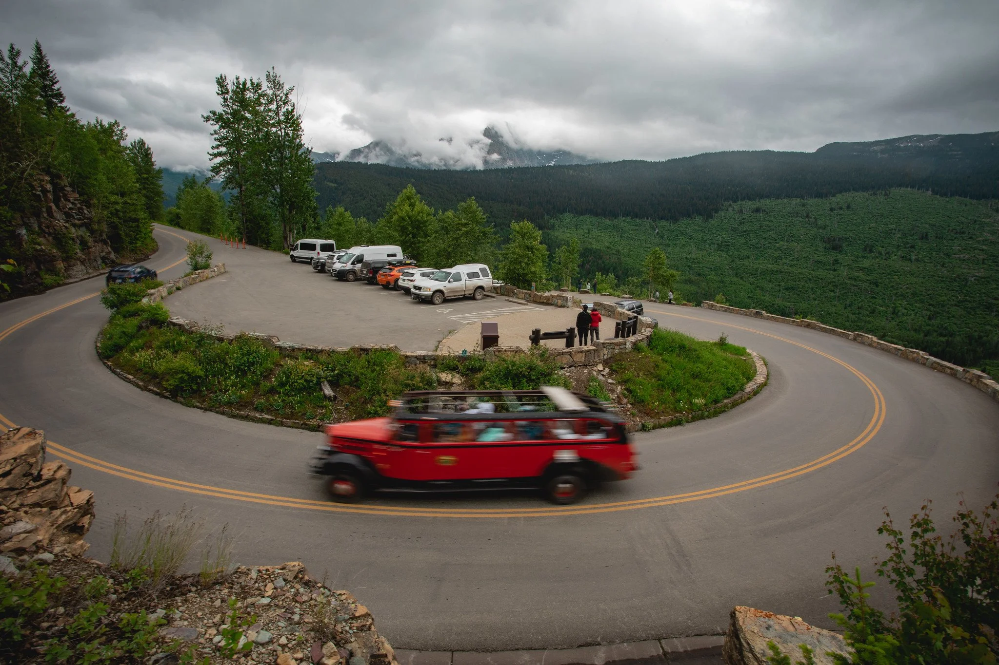 A blurred Red Bus takes the turn at Crystal Point in Glacier National Park