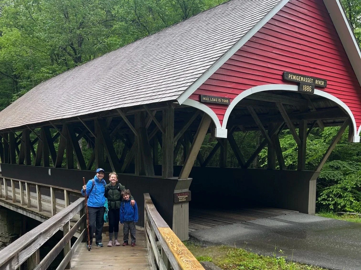 The author and her 2 children standing next to a red covered bridge in New England
