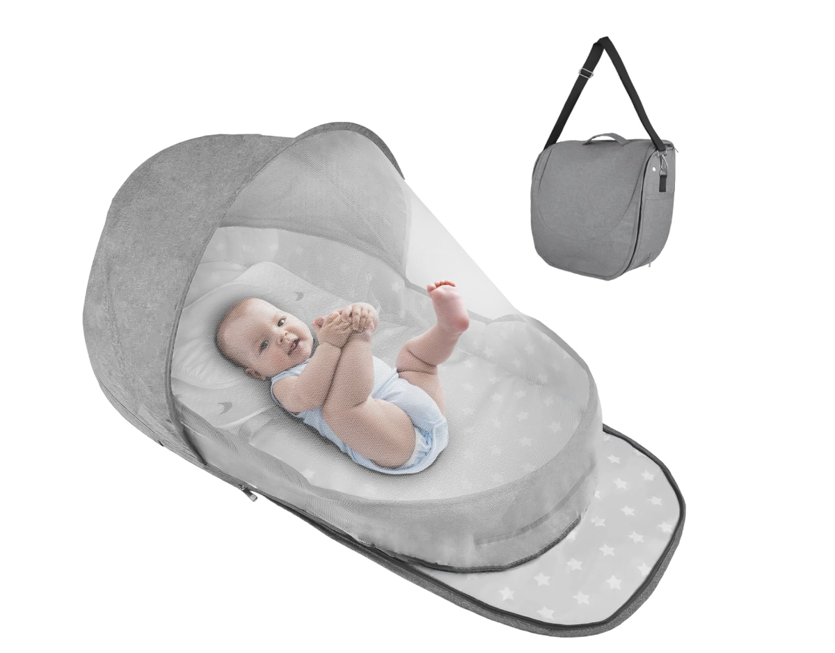 Baby holds foot while laying on its back in the portable travel bassinet