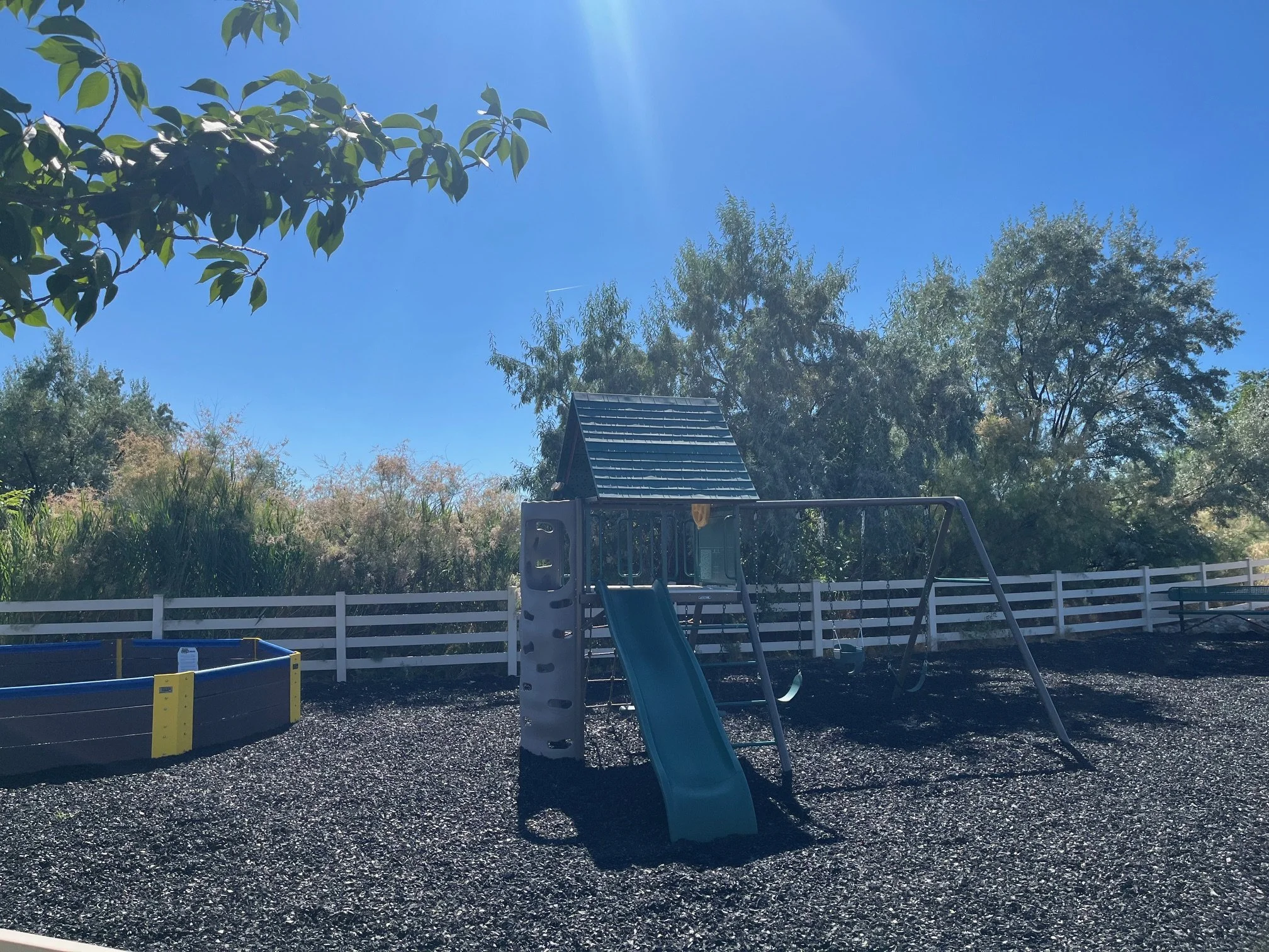 Playground equipment with mulch underneath and gaga ball pit to the left