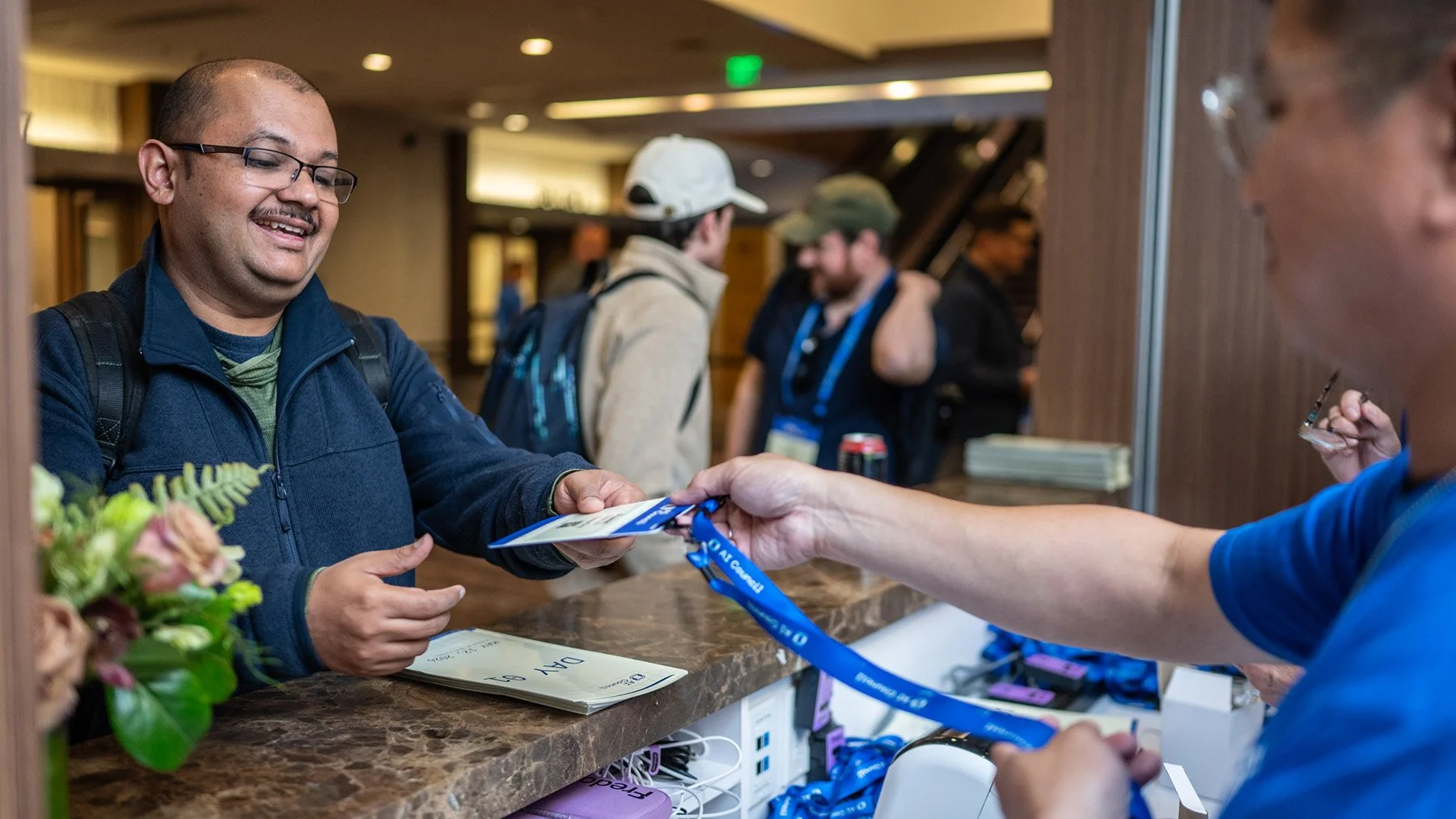 Attendee checking in and receiving a badge at the AI Council conference registration desk.