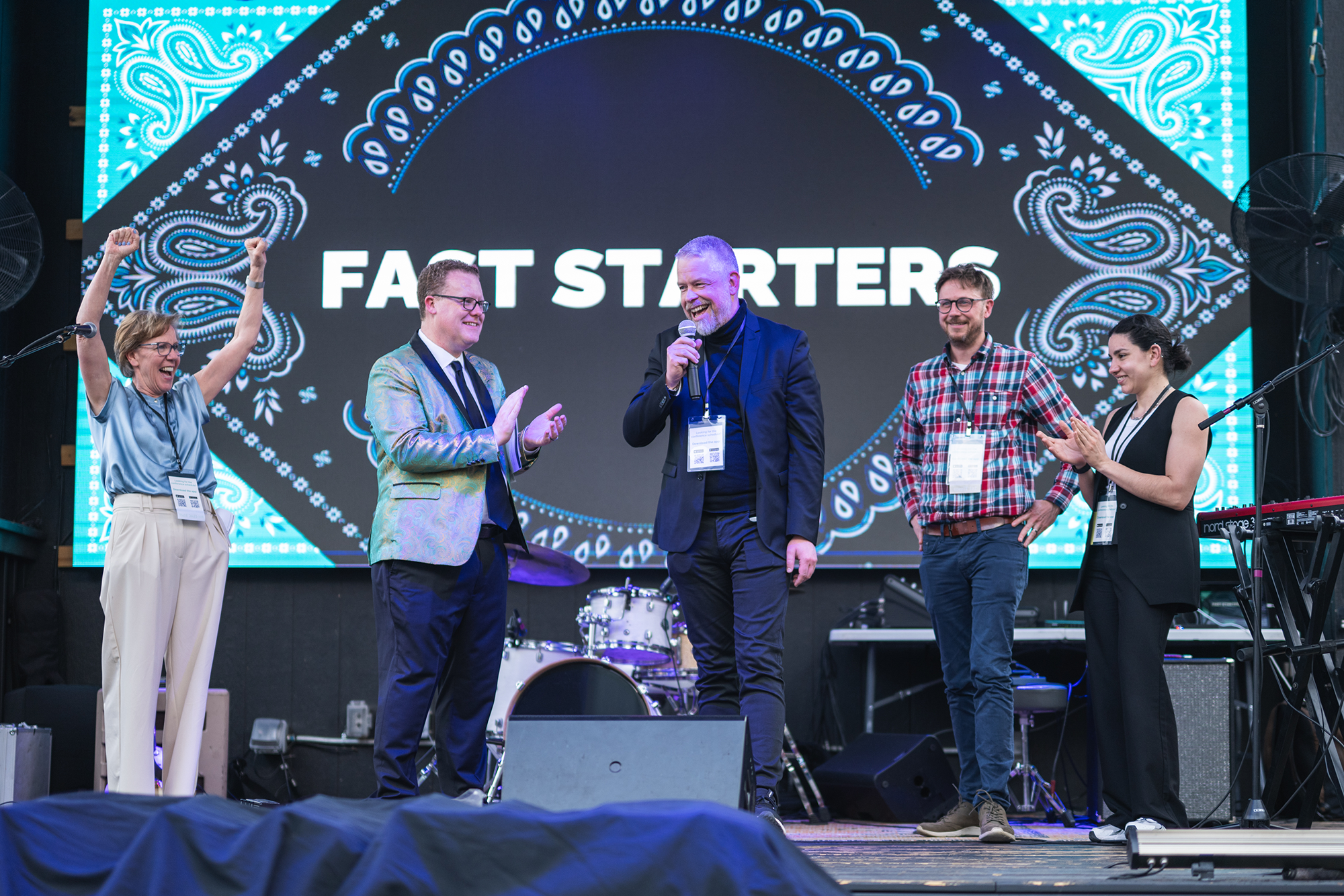 Lively stage entertainment at an Austin corporate summit featuring speakers and performers on stage in front of a large, custom-branded digital backdrop.