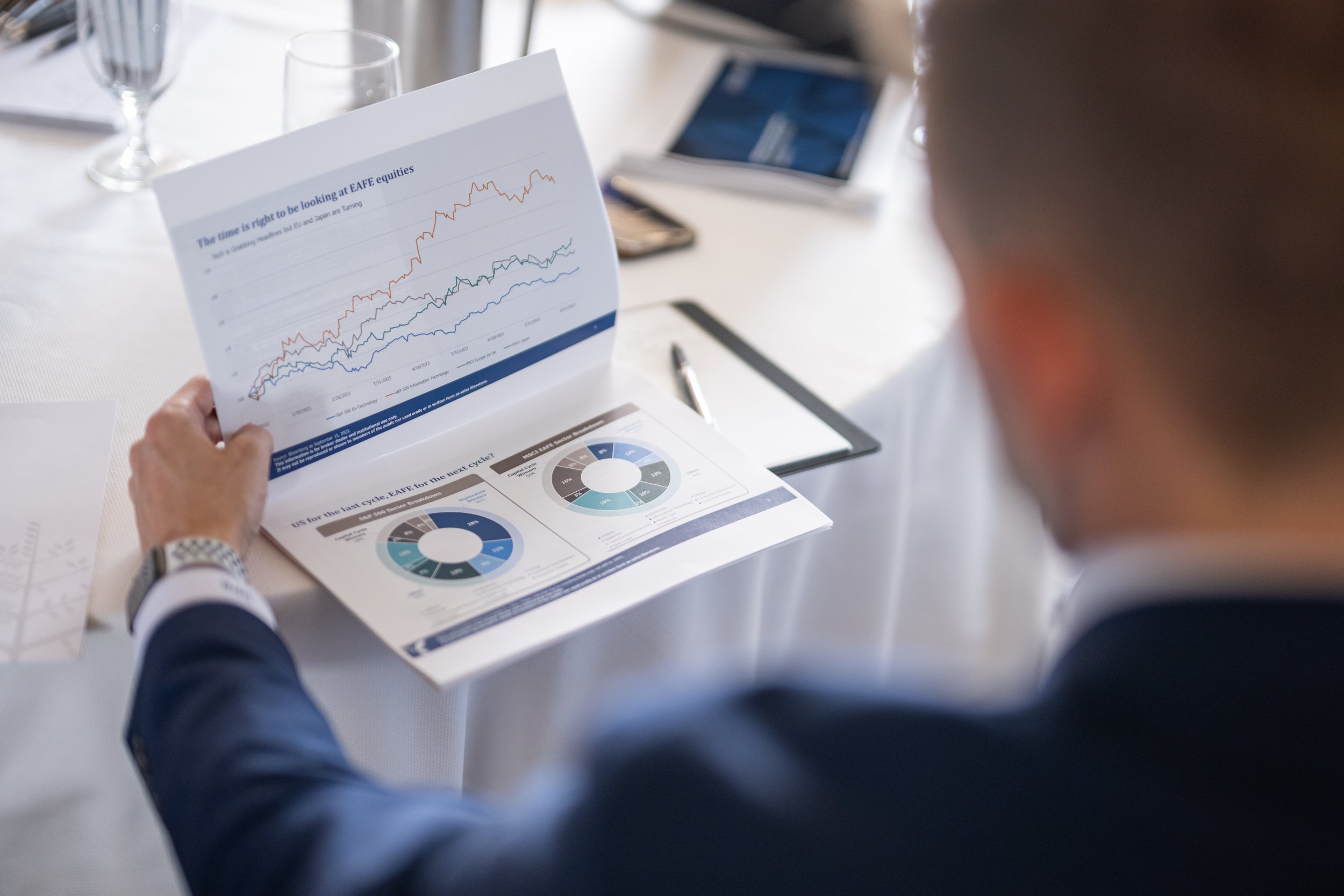 High-quality corporate photography capturing a close-up of financial reports and data visualization during a professional executive workshop.
