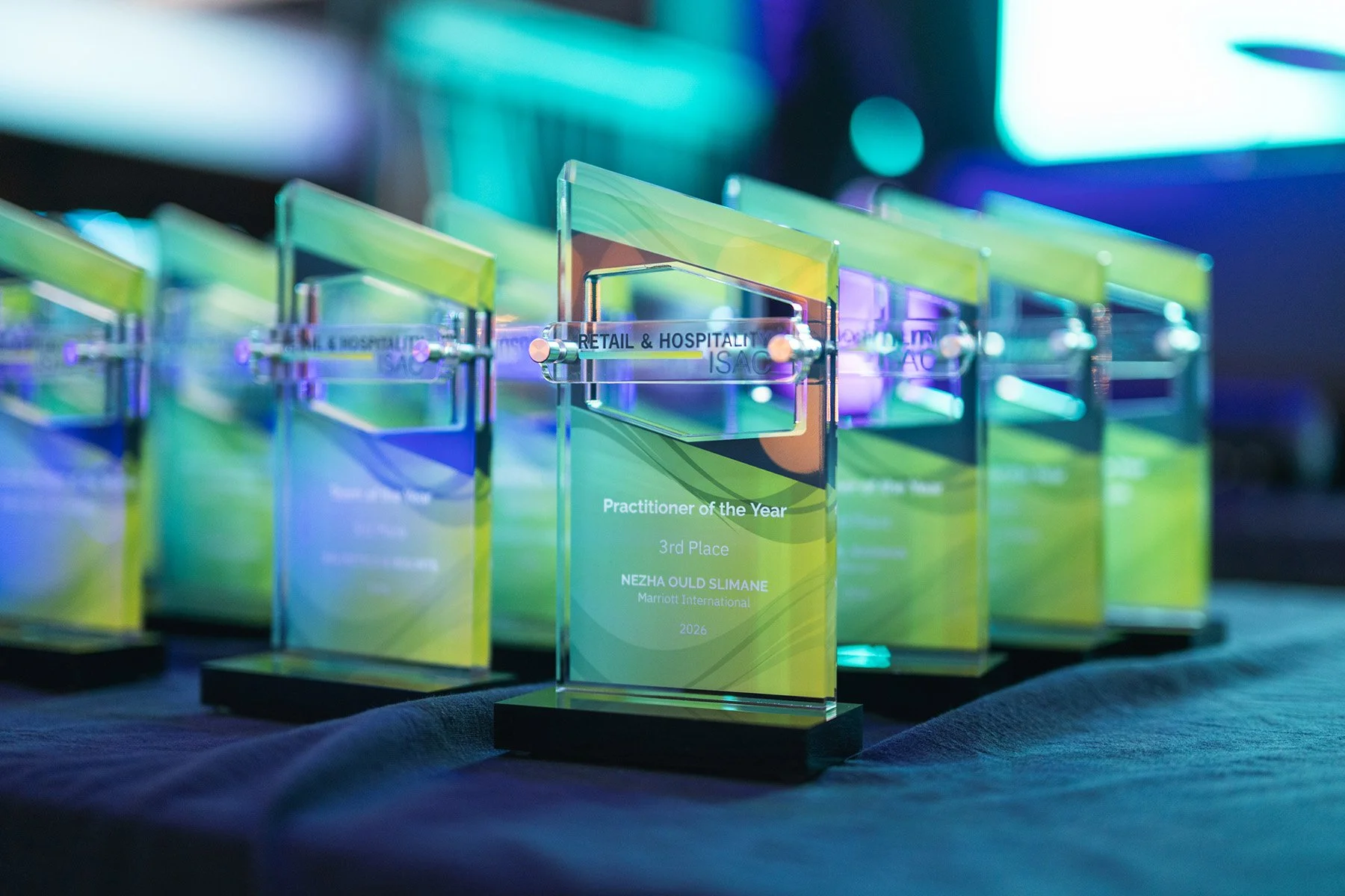 Detail shot of custom Retail & Hospitality ISAC glass awards lined up on a table for an industry recognition ceremony, captured by an Austin corporate event photographer.