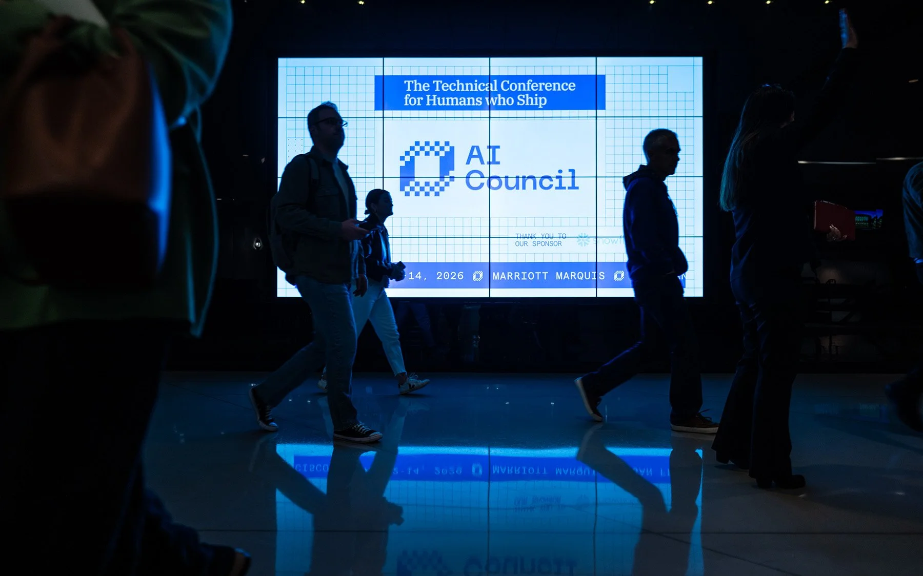 AI Council conference attendees walking in front of the stage display at a technology conference in San Francisco.