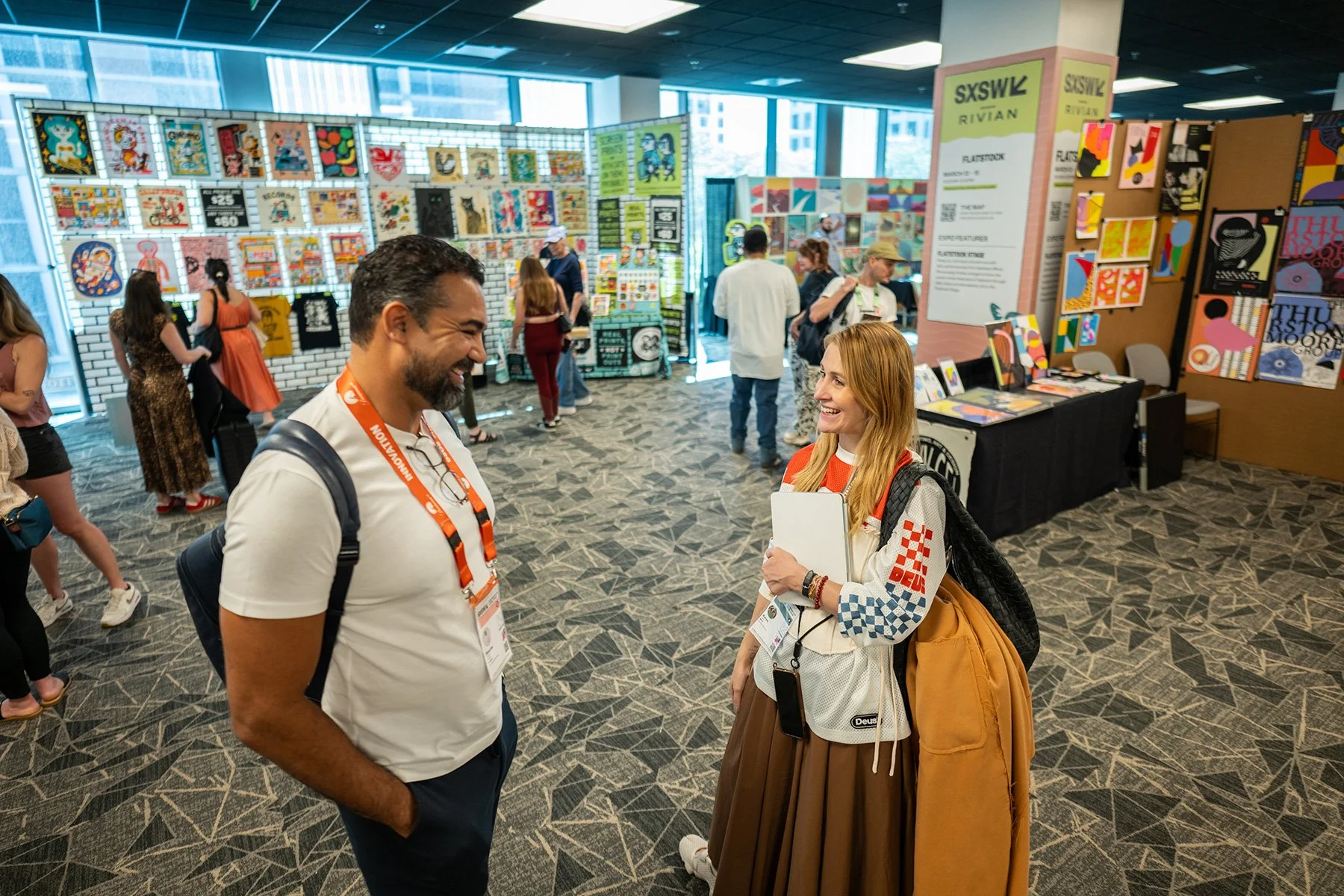 SXSW 2026 Flatstock poster exhibition in Austin, Texas. Candid conversation between two attendees. High-end event photography by Tico Mendoza Studios.