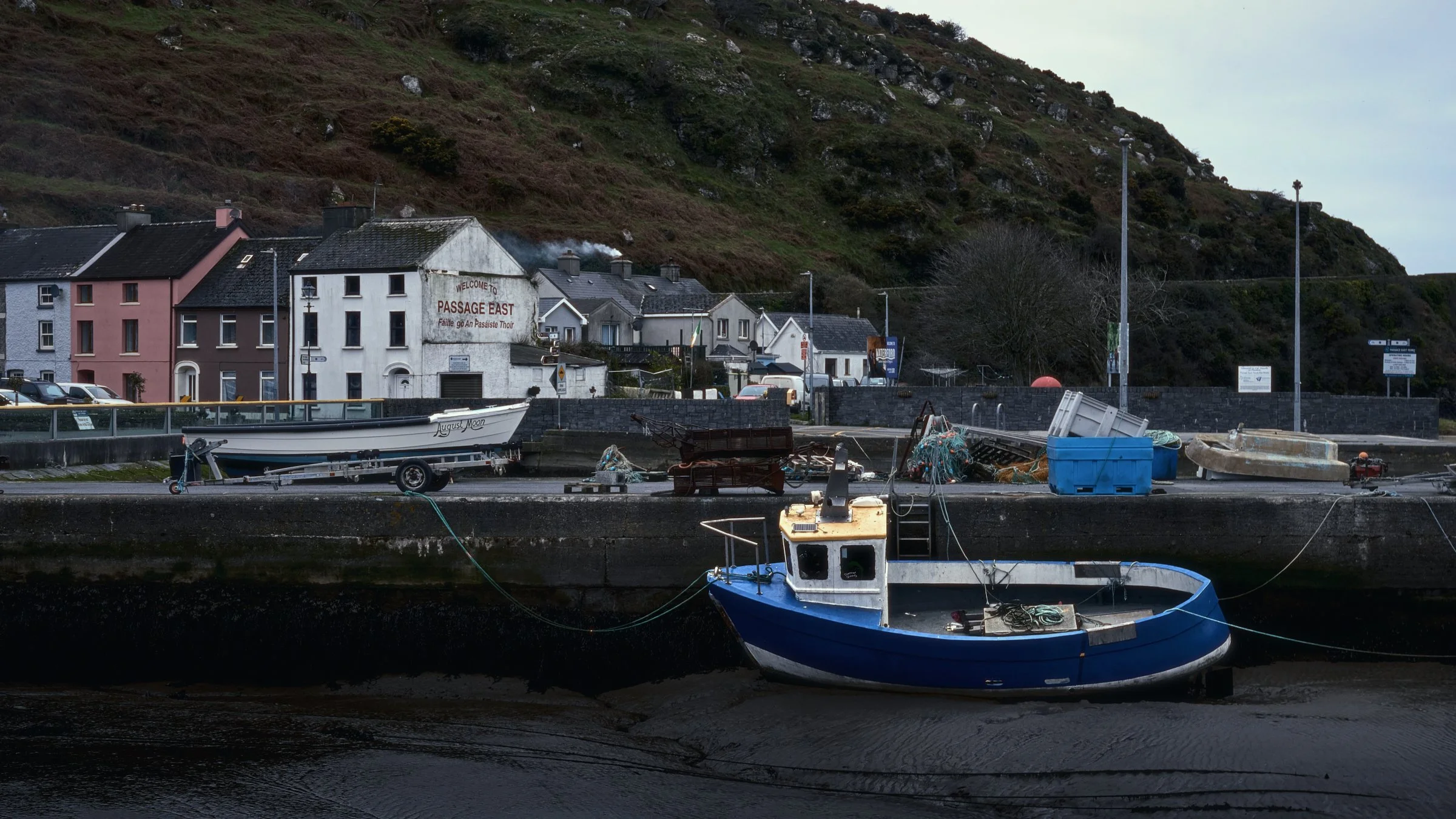 One Take - Ireland "At Low Tide", Passage East, Co. Waterford, Ireland 2025. A cinematic color photograph at low tide in Passage East harbour with a boat tied to the pier. The boat is sitting in the mud waiting for the tide to rise.