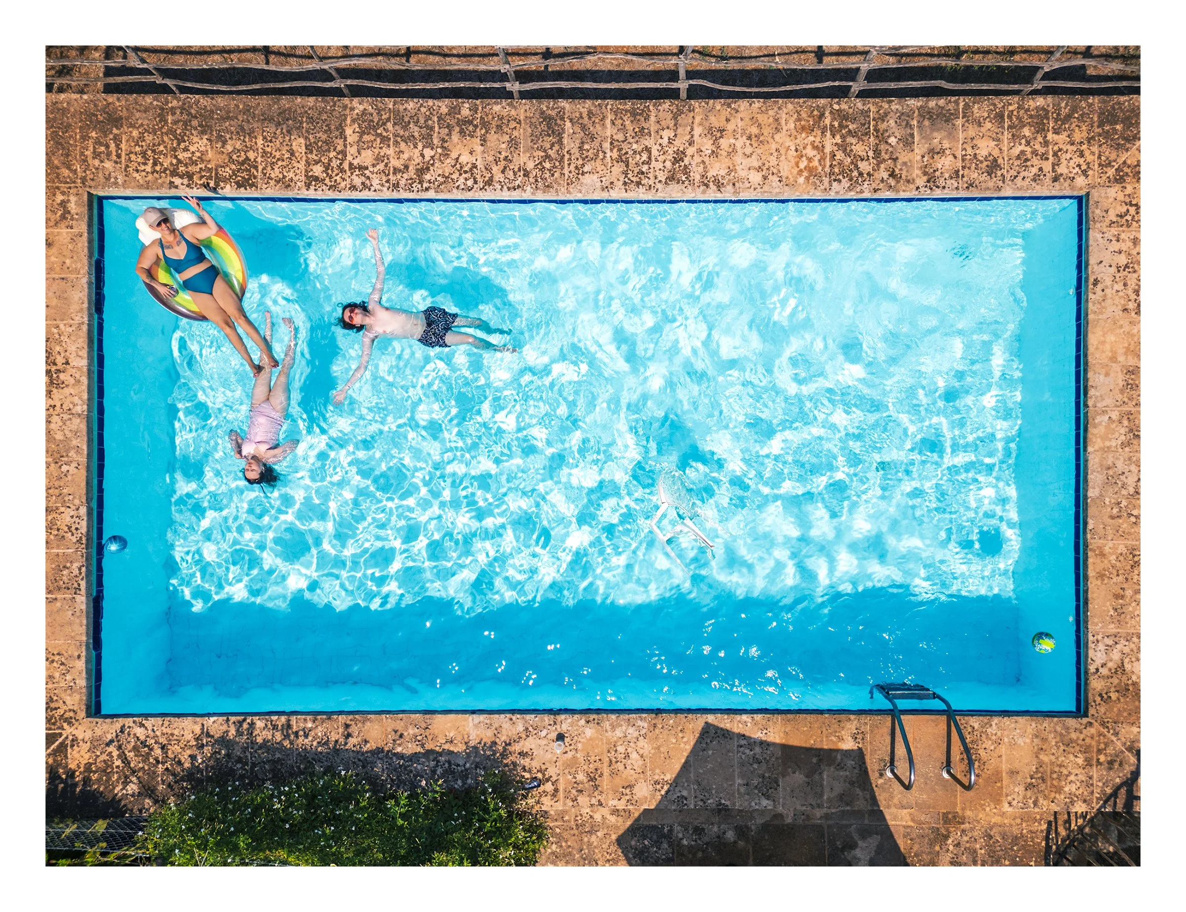Family on holiday in Mallorca, Spain, 2025 photographed by Dave Haworth. Color top down drone photograph of family floating in bright blue water of a Spanish Villa pool.