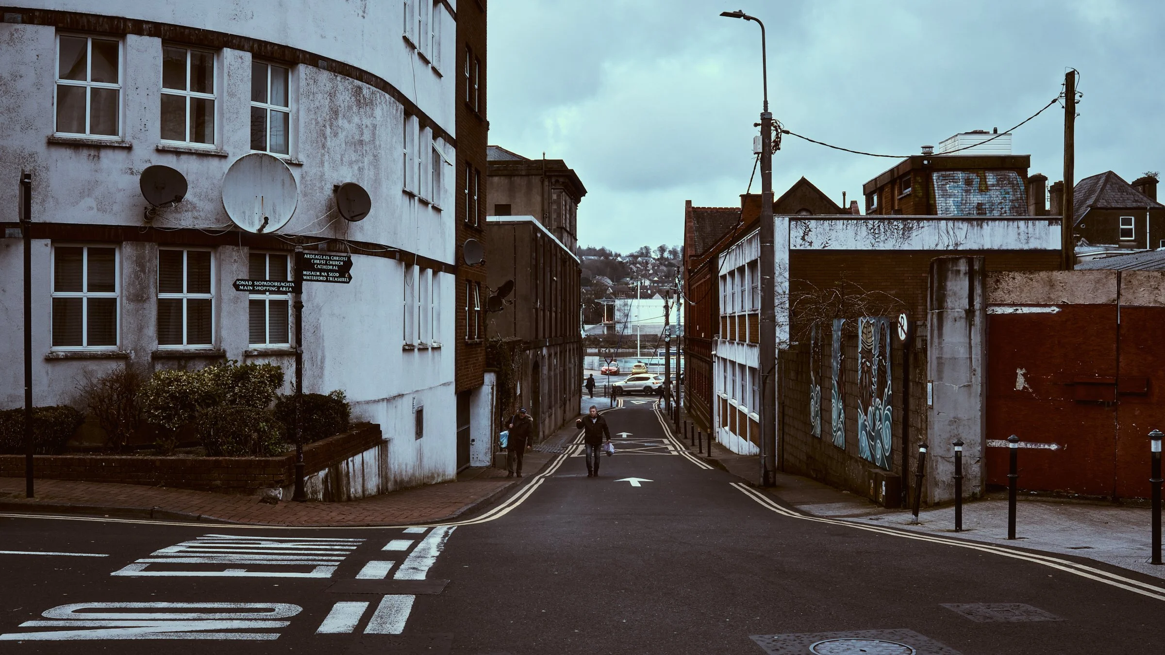 One Take - Ireland "Owning The Street", Keyser Street, Waterford, Ireland 2026. A cinematic color photograph of two men walk up an empty street in Waterford City Centre. Photograph by Dave Haworth.