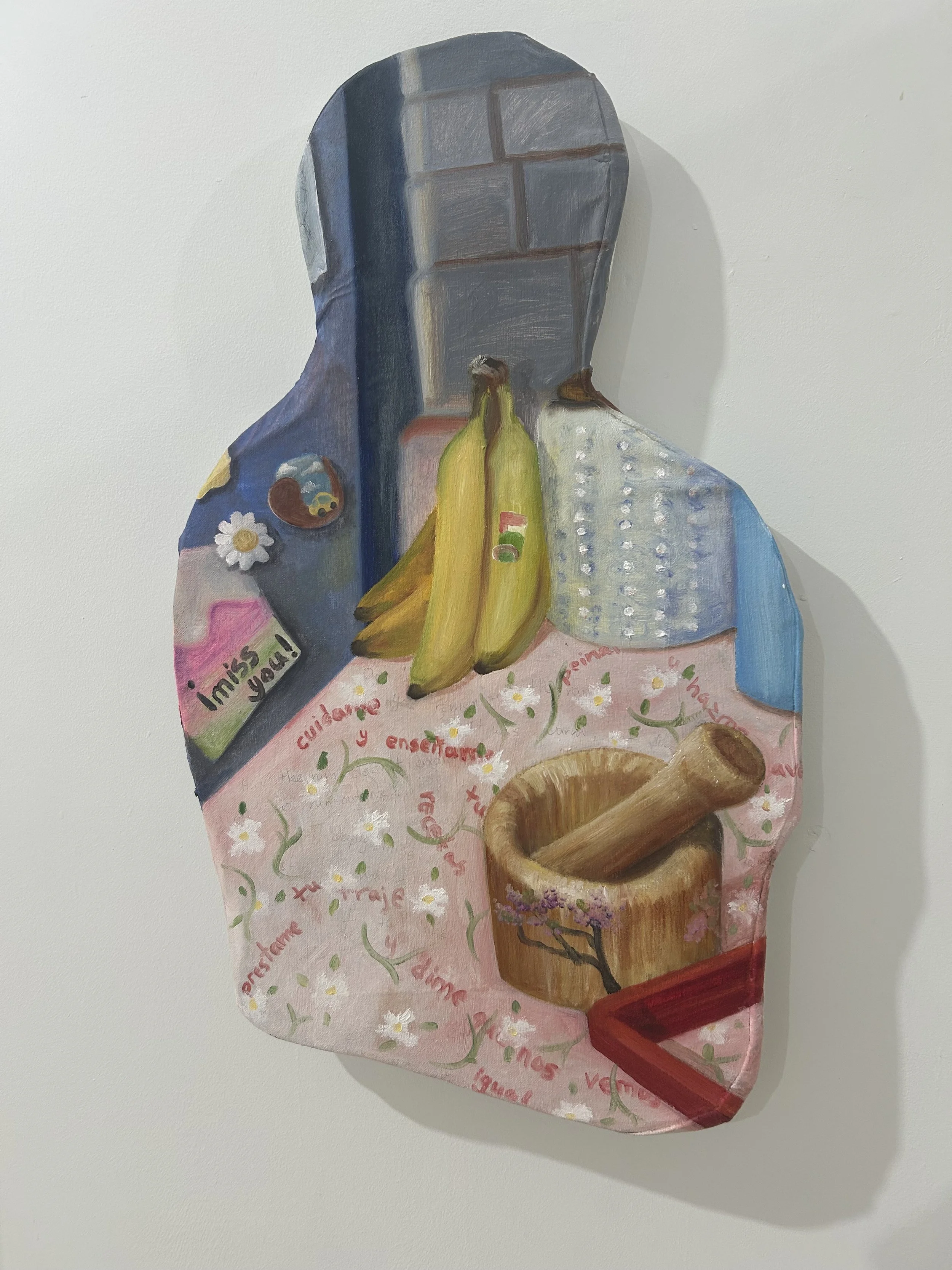 A painted wooden cutout of a person's profile with a dark hat, white shirt, and pink apron, decorated with flowers, a daisy, bananas, religious symbols, and words in French such as 'merci', 'vous', and 'enfants'.