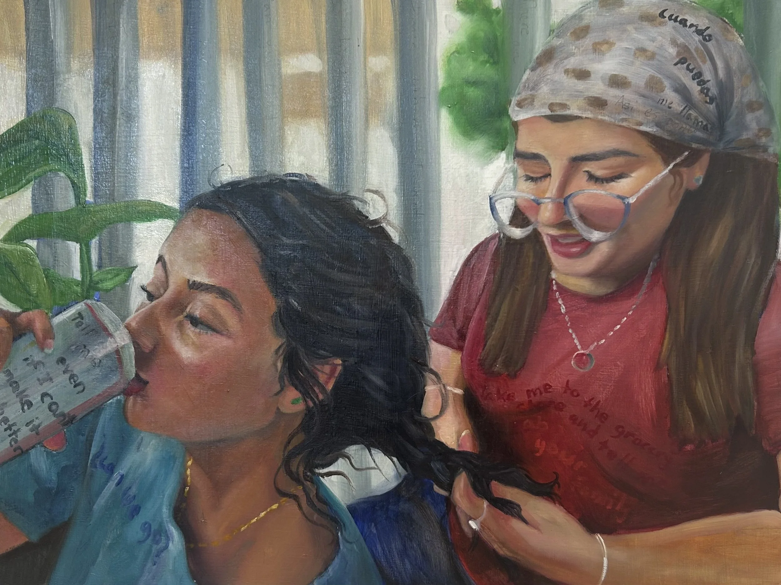 Painting of two women, one with long black hair wearing a blue shirt and a necklace, the other with long brown hair, glasses, a gray headscarf with brown spots, and a red shirt, smiling as they look at something together.