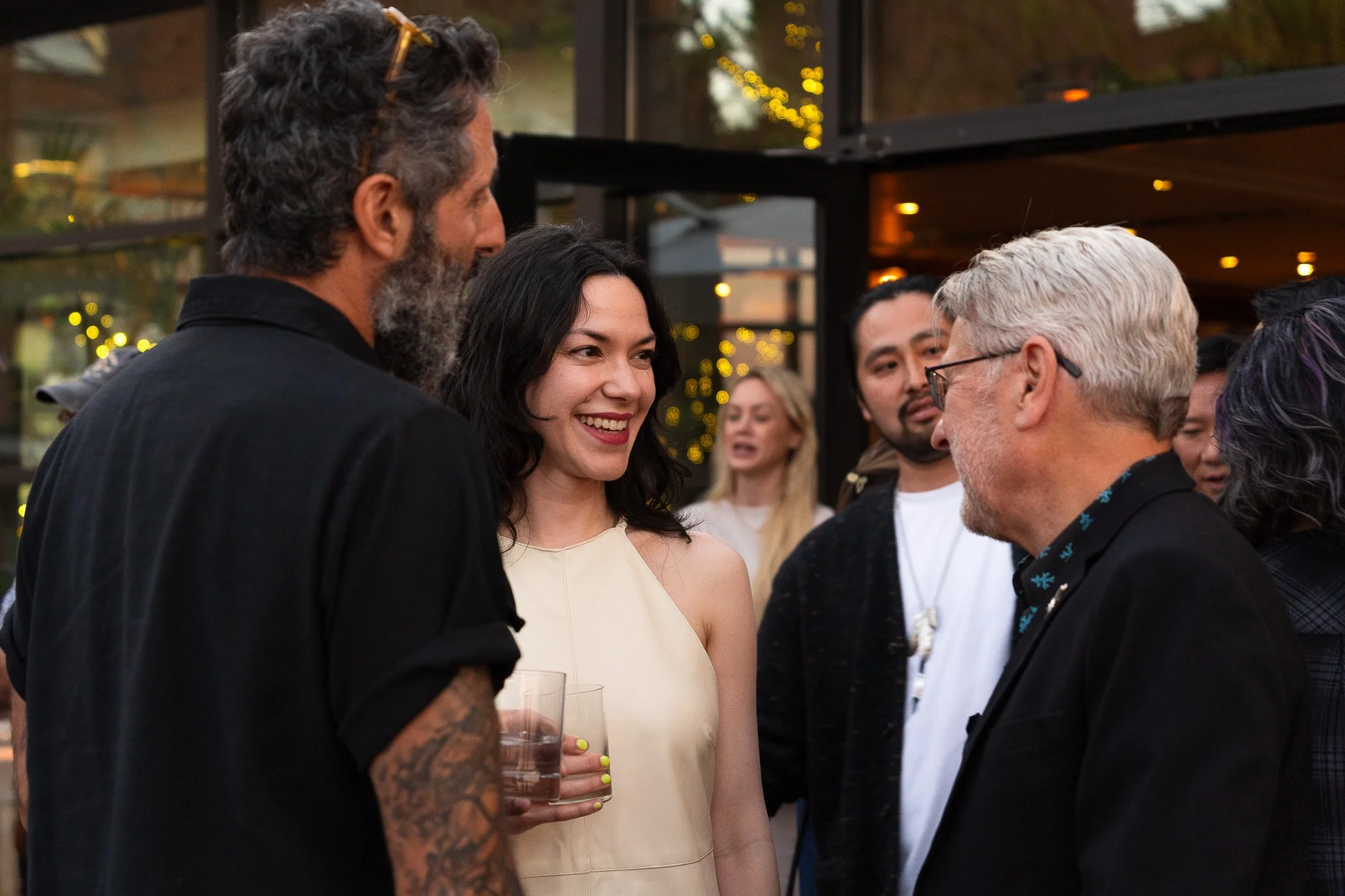 People socializing at a party outside in San Francisco, engaging in conversation and smiling.