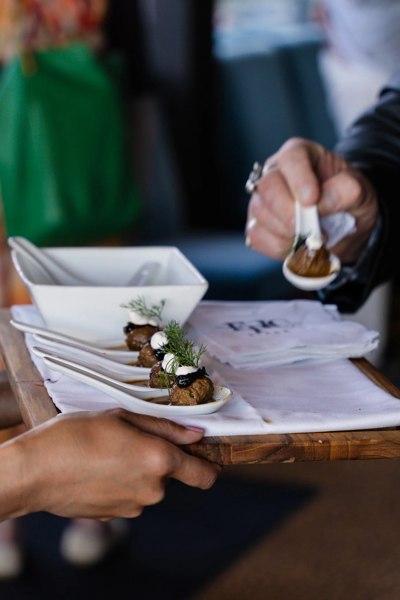 A person serving gourmet appetizers on ceramic spoons at a restaurant in San Francisco. 