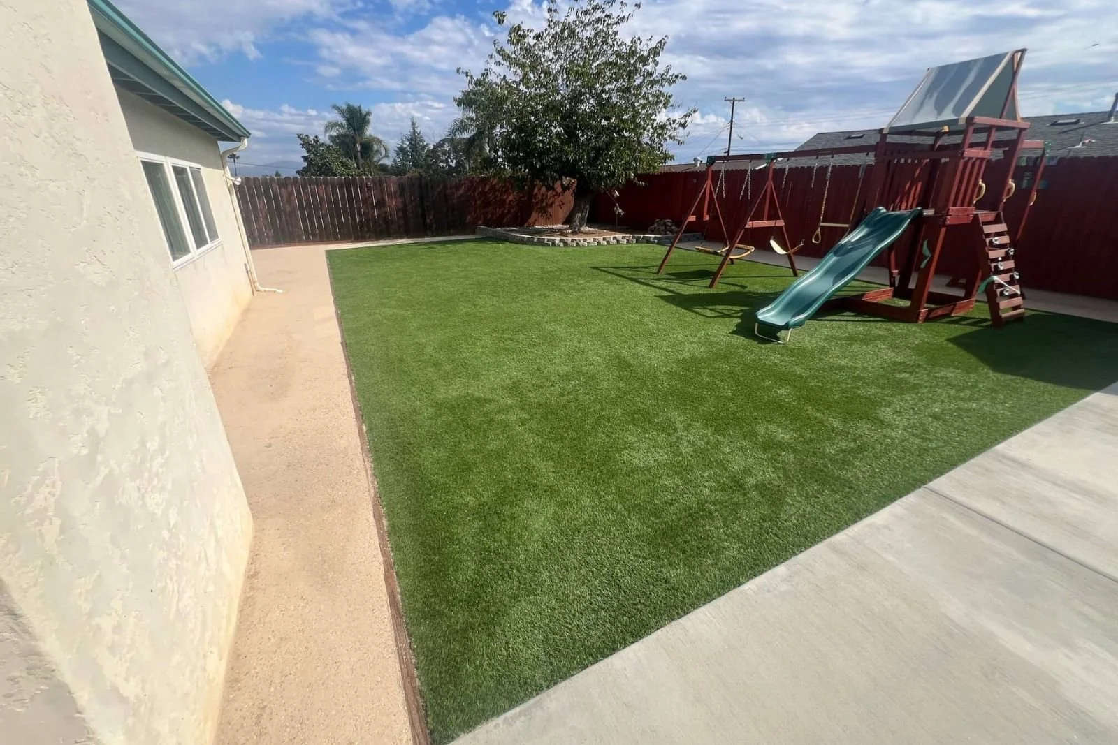 Beautifully refreshed landscaping in Santee backyard, showcasing the completed project with kids play set ready for family fun