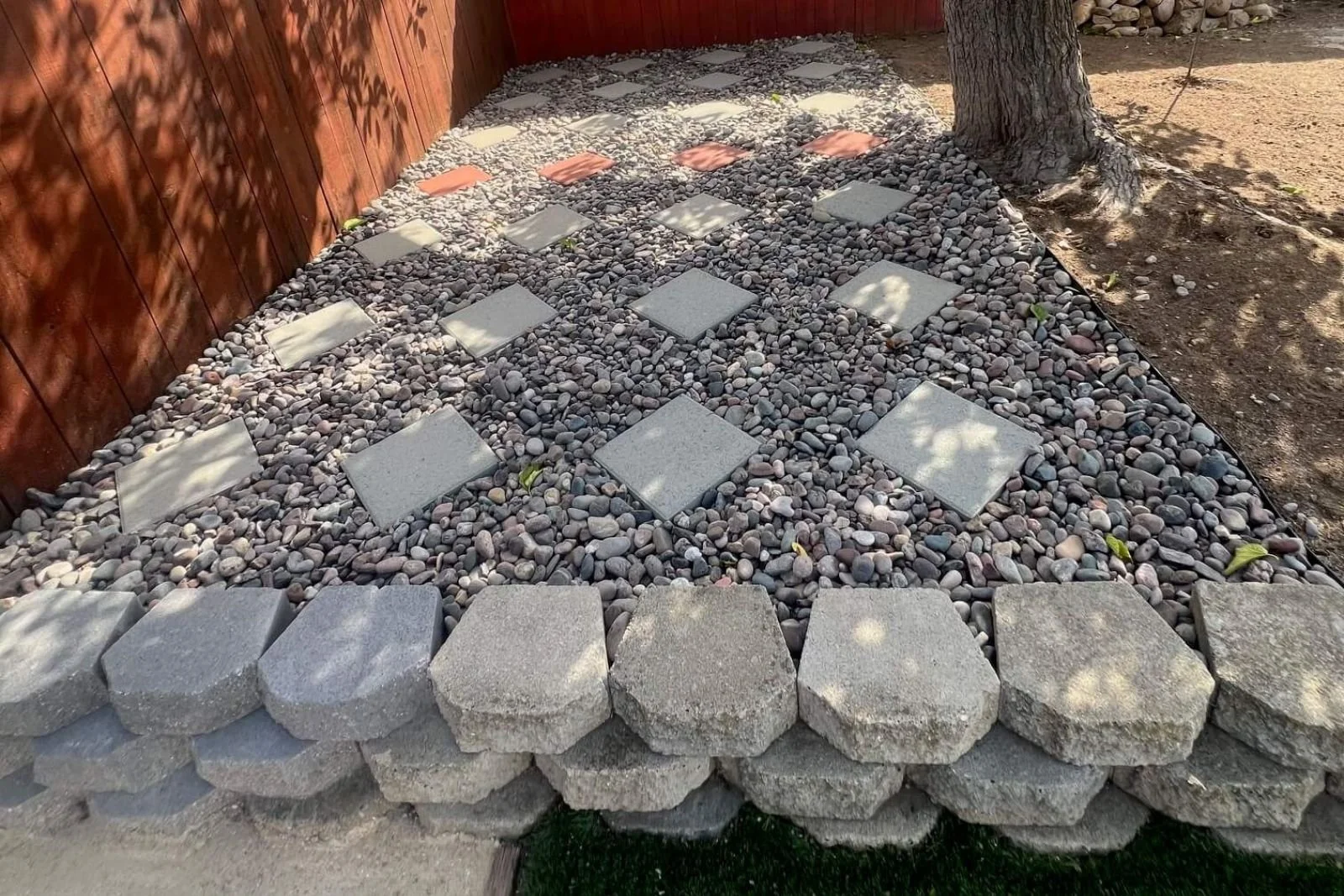 Garden wall with rocks and steps near artificial turf